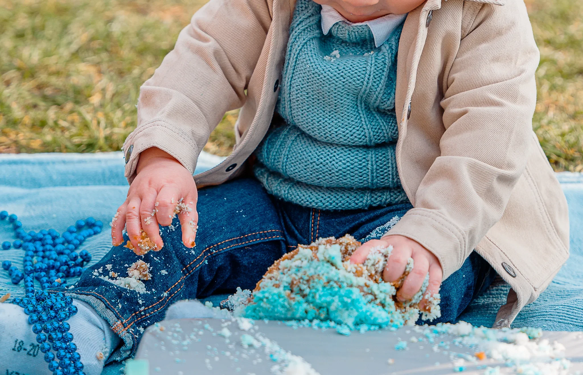 Bébé s'amusant à écraser son gâteau d'anniversaire sur un tapis de pique-nique au Trocadéro.