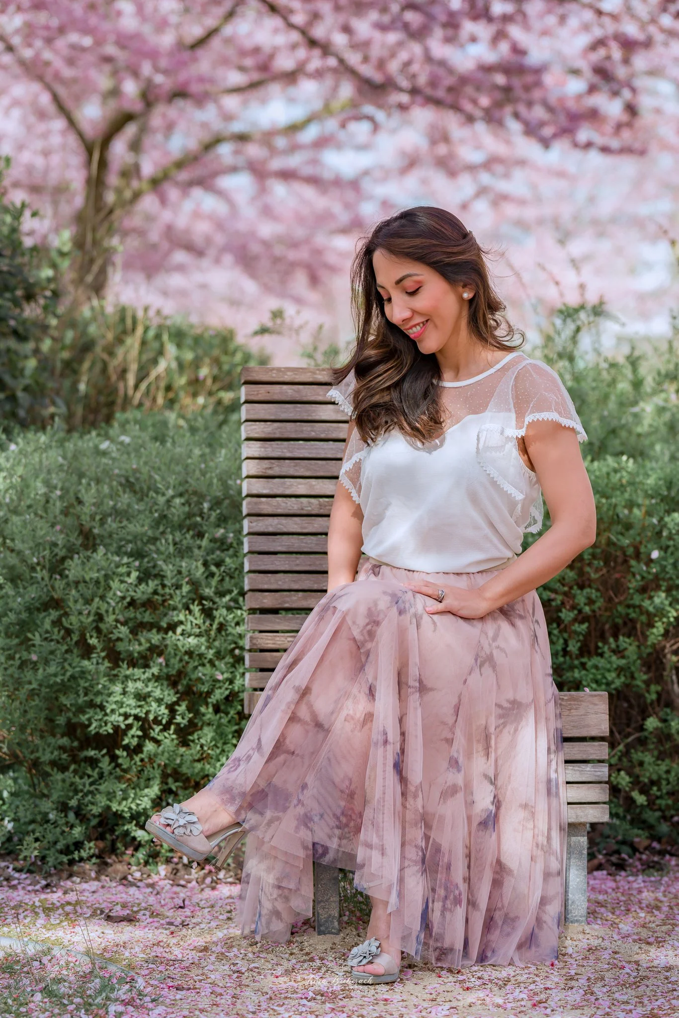 Femme souriante et élégamment habillée assise devant les cerisiers Japonais