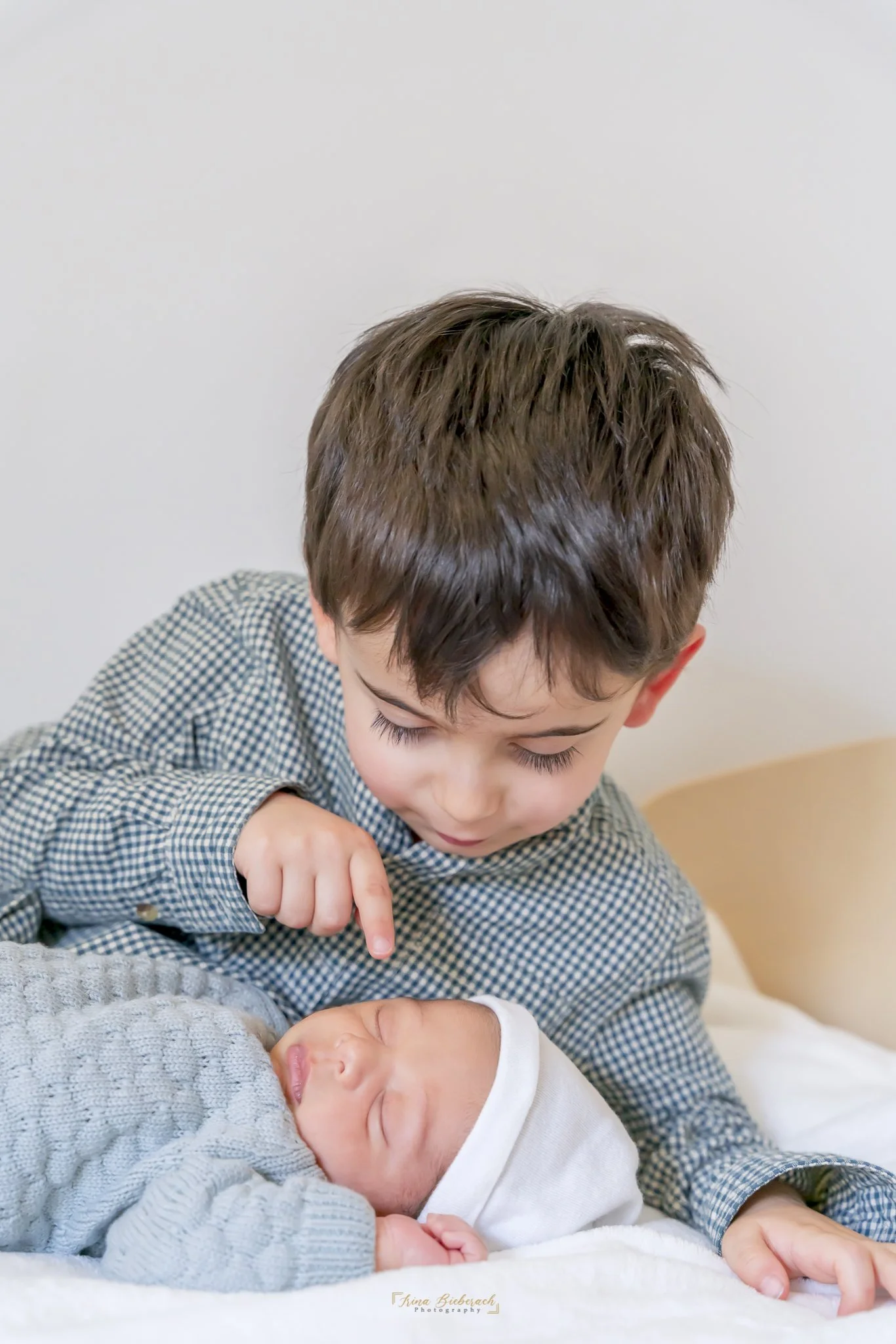 Petit garçon essaye de toucher le visage de son bébé frère qui dort devant lui