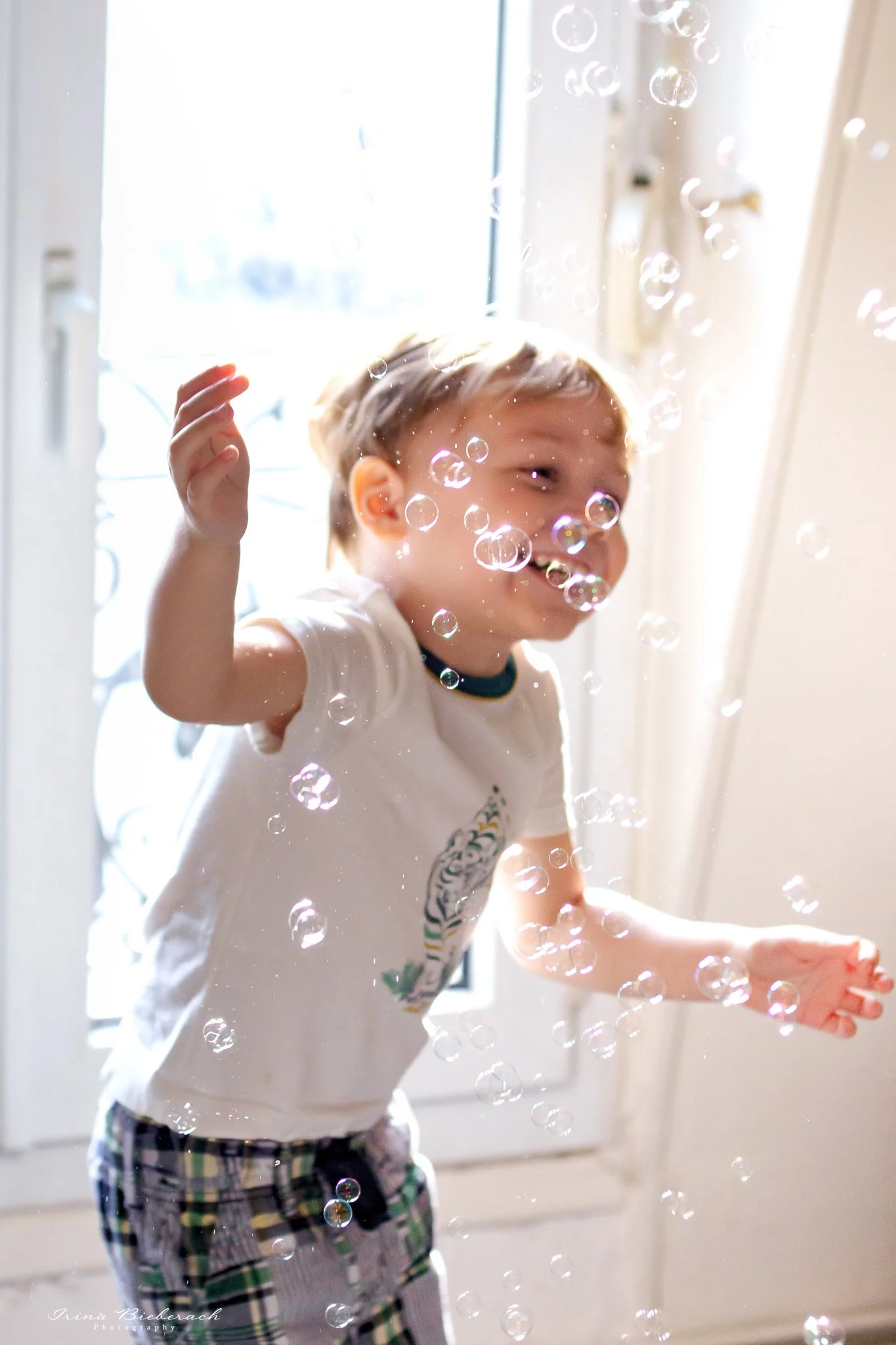 Petit garçon sourit entre les bulles de savon dans un appartement