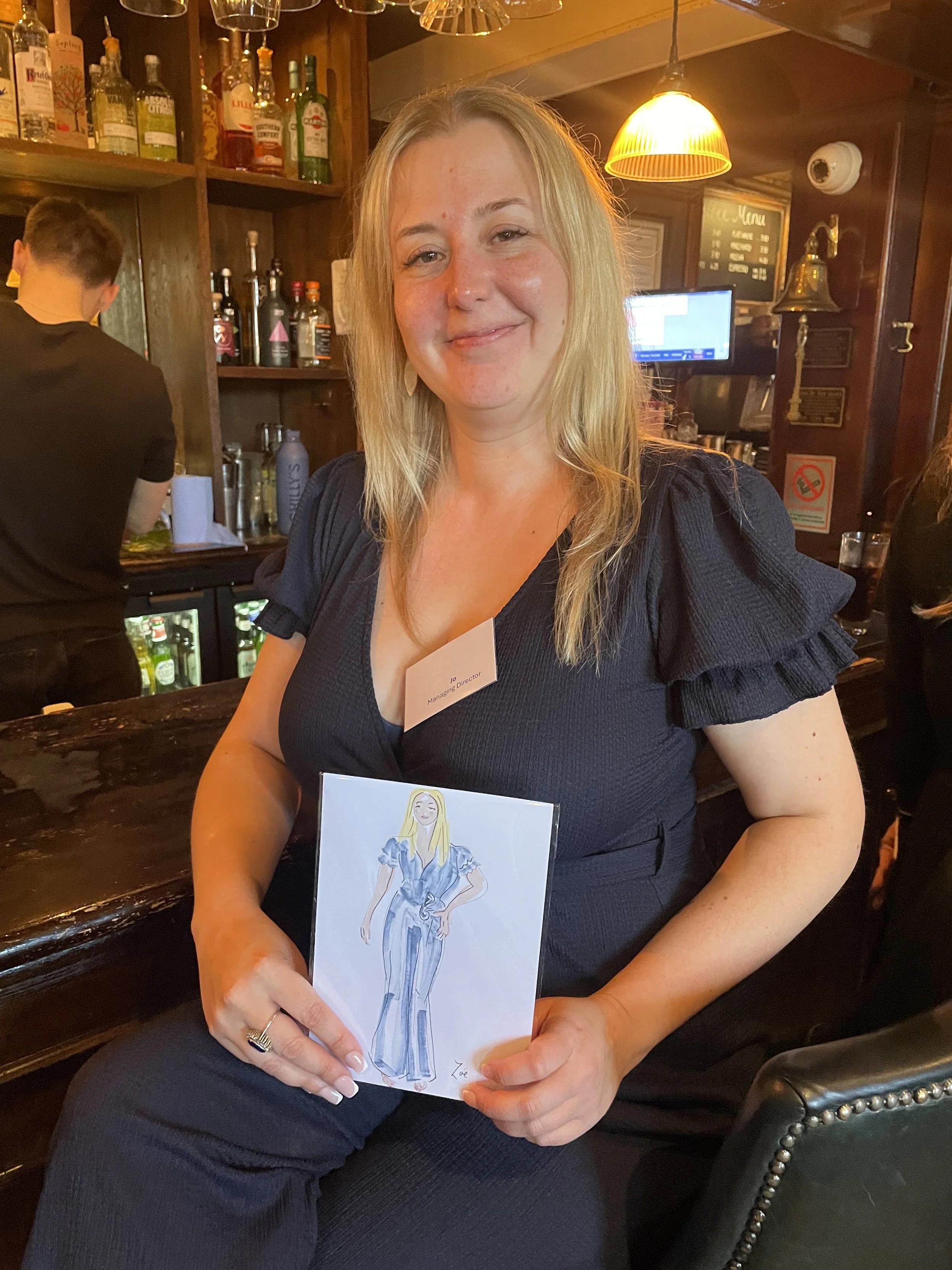 Happy customer with long blonde hair holds live illustration by Zoe Parker illustration at event by Bells Accountants.JPEG