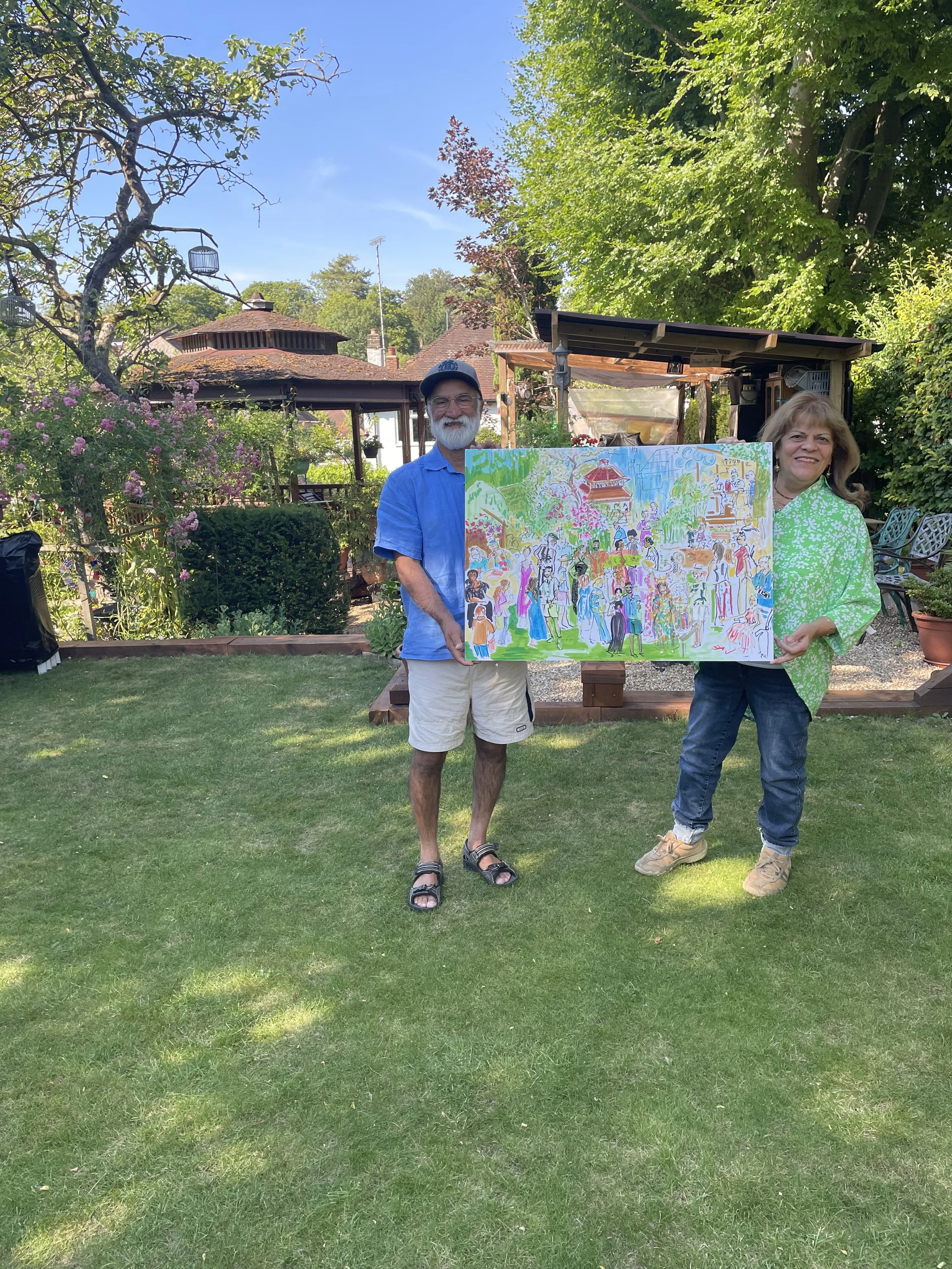 Garden Party hosts are holding the artwork created for their birthday garden party. They are smiling and holding the A1 size image created by Zoe Parker Illustration, featuring brightly coloured guests in party clothes.