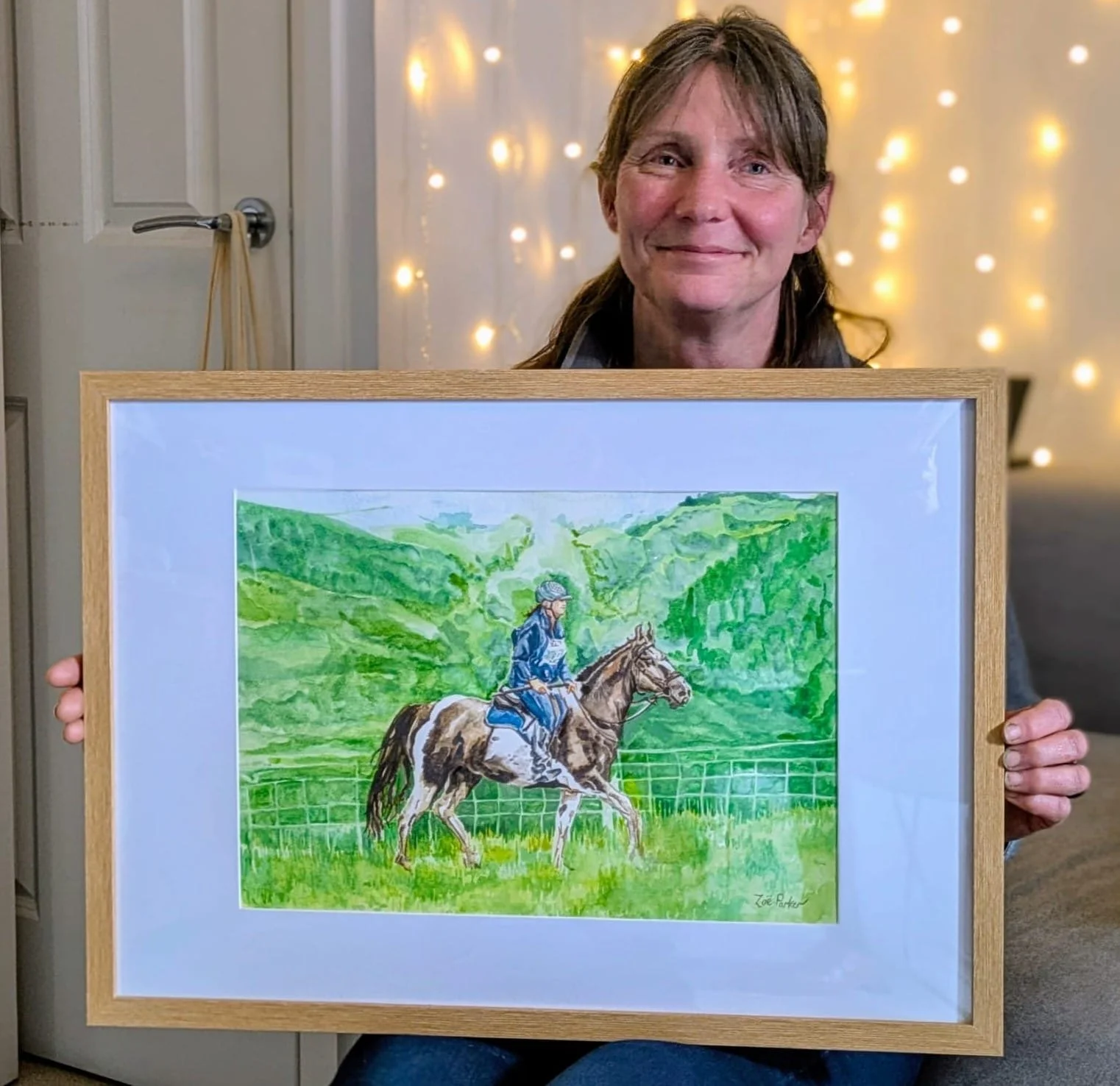 Watercolour portrait illustration featuring horse and rider for 50th birthday gift, framed held by birthday recipient illustrated by Zoe Parker Illustration.png.JPG