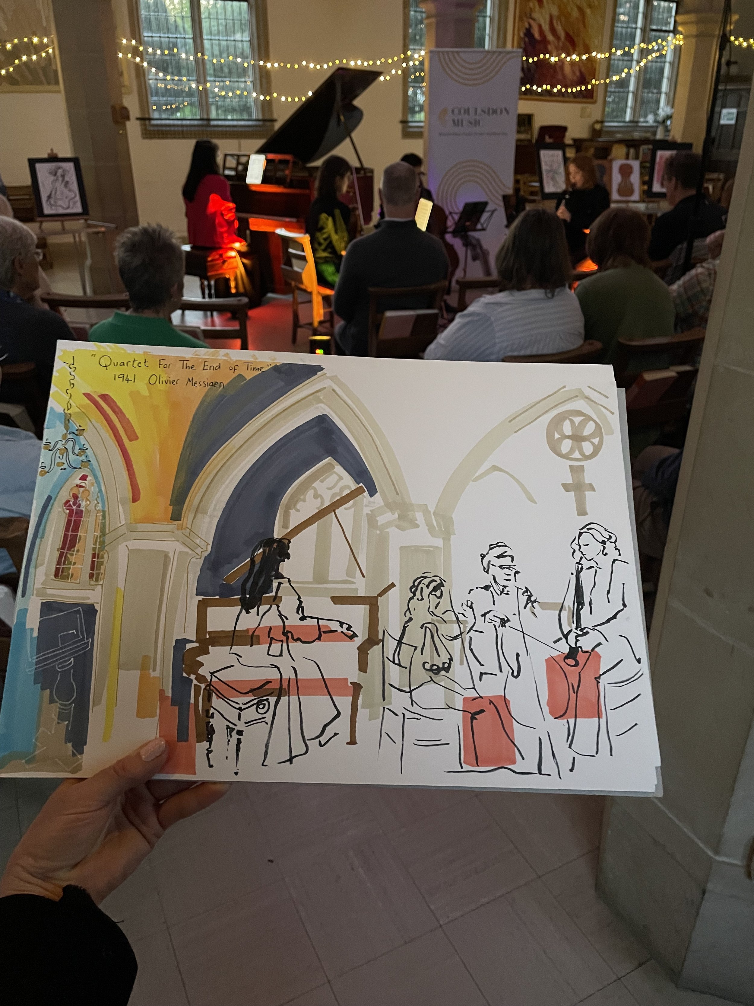 Zoe Parker Illustration holds up a drawing of a musical recital in a church. She creates the drawing as a live graphic recording whilst the music is playing