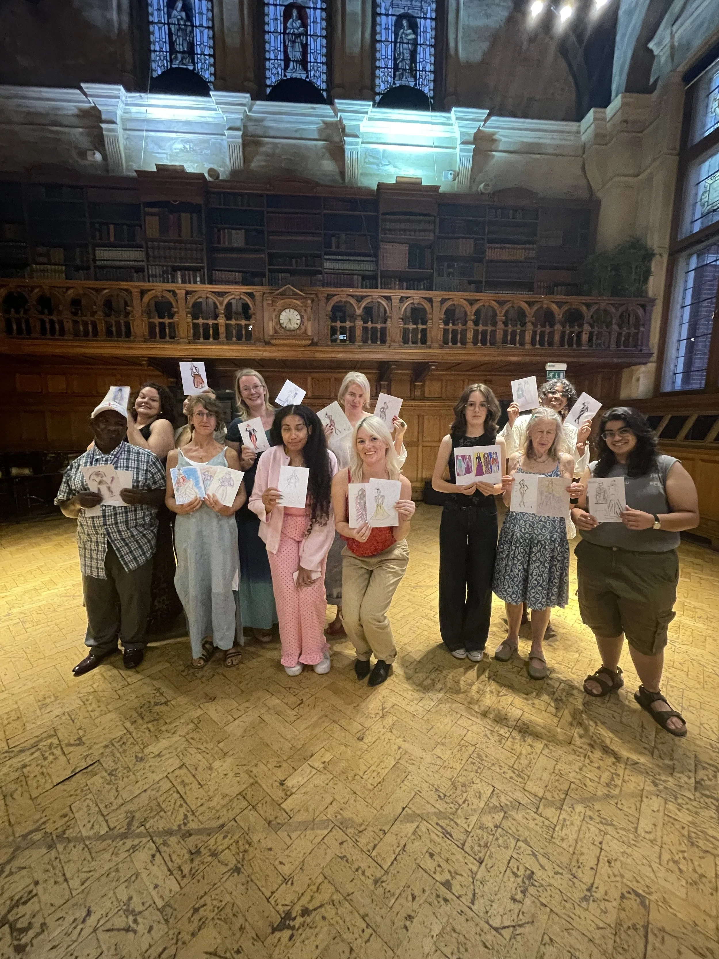 A group of happy people showing their new-found drawing skills at a Dress Up and Draw fashion illustration workshop run by Zoe Parker Illustration at Braithwaite Hall at the Museum of Croydon, London