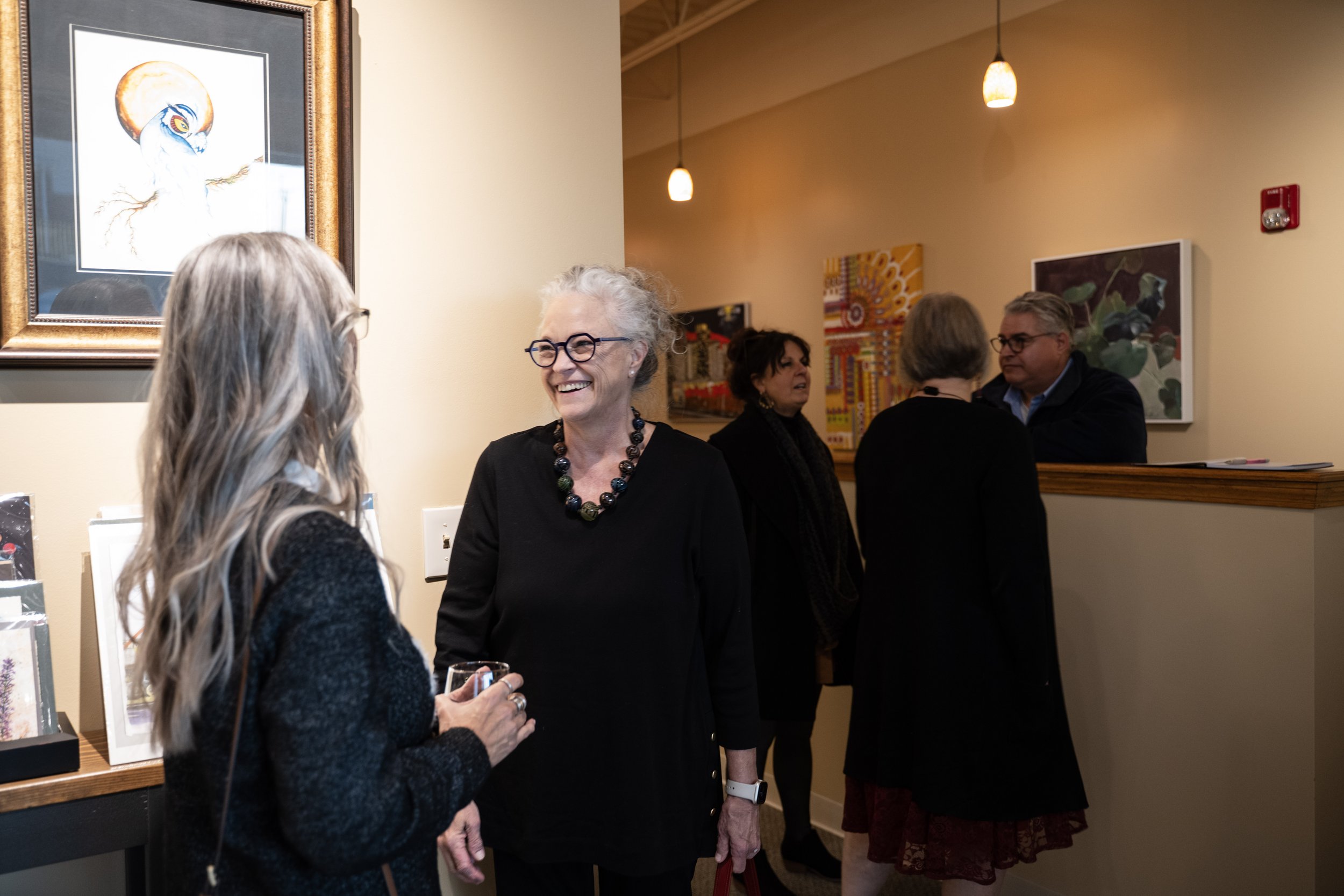 Group of people at The Fusion art gallery at Parkville Frame Gallery, engaging in conversation, with artwork on the walls behind them.