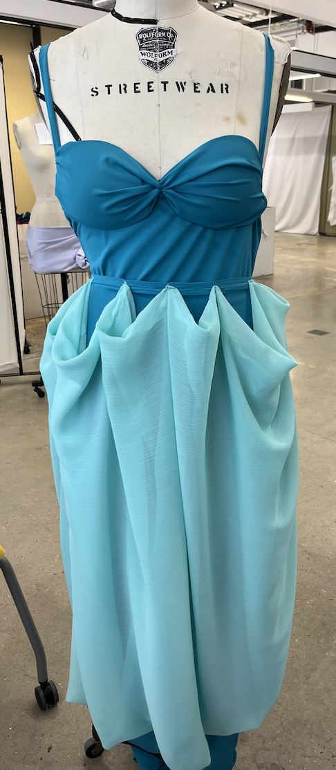 Crêpe gown with crossed spaghetti straps, neck scarf, and removable draped overskirt via snaps in the back.