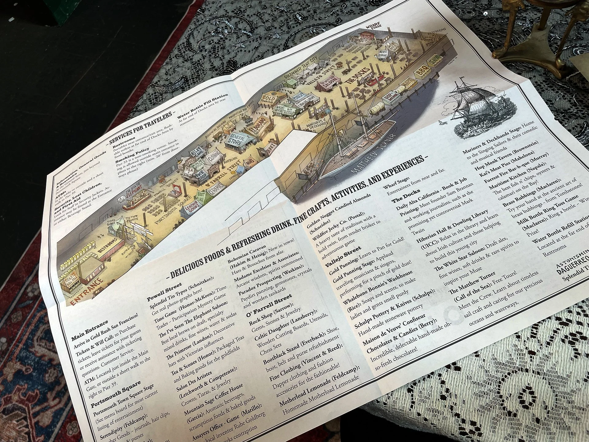 Inside of event program featuring a detailed map of a boardwalk and seaside area with labeled locations such as shops, stages, and attractions, including the Wharf Stage, Gold Miner Tent City, and several food and activity stalls.