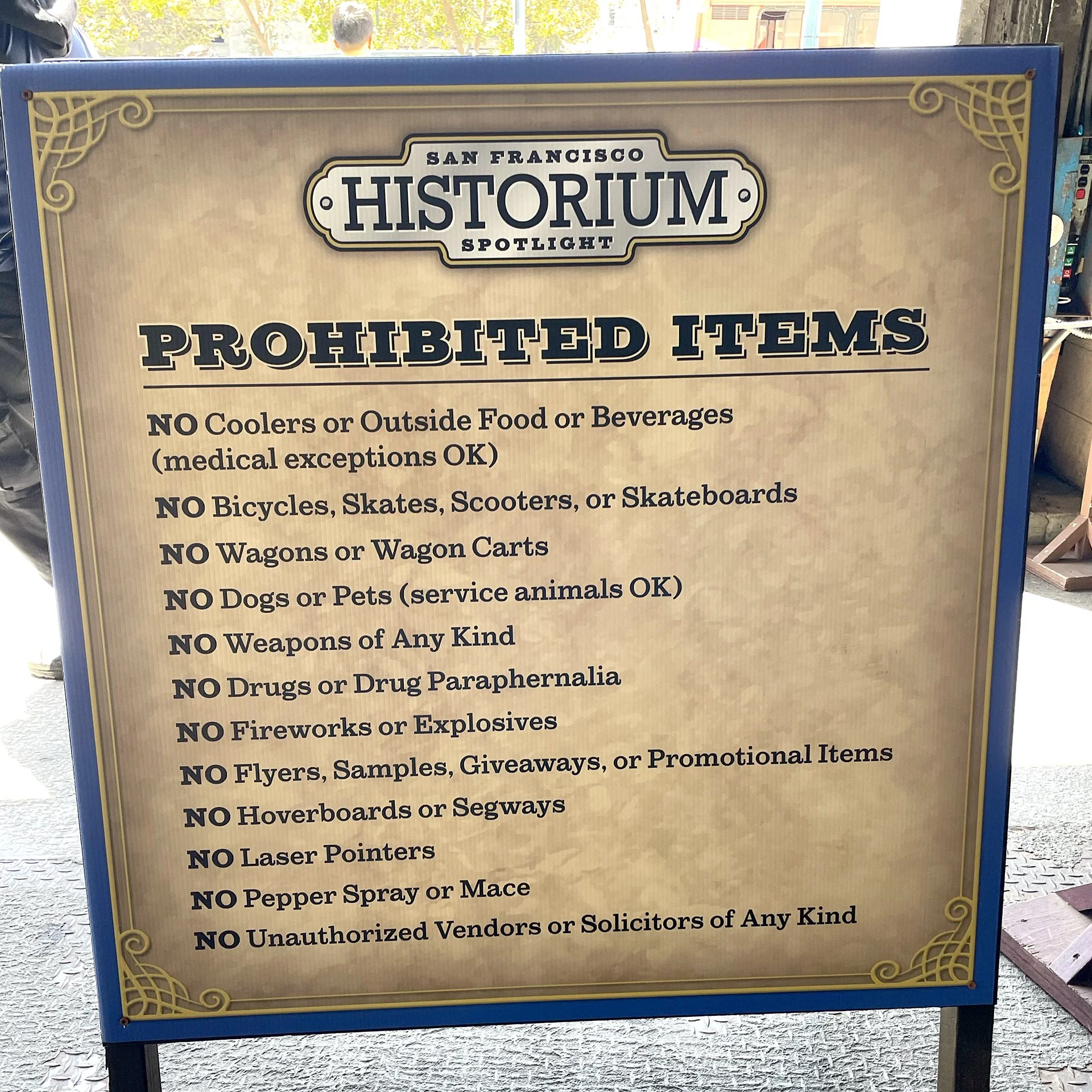 Signboard at San Francisco Historium Spotlight listing prohibited items including alcohol, bicycles, skateboards, weapons, drugs, fireworks, laser pointers, pepper spray, unauthorized vendors, and pets.