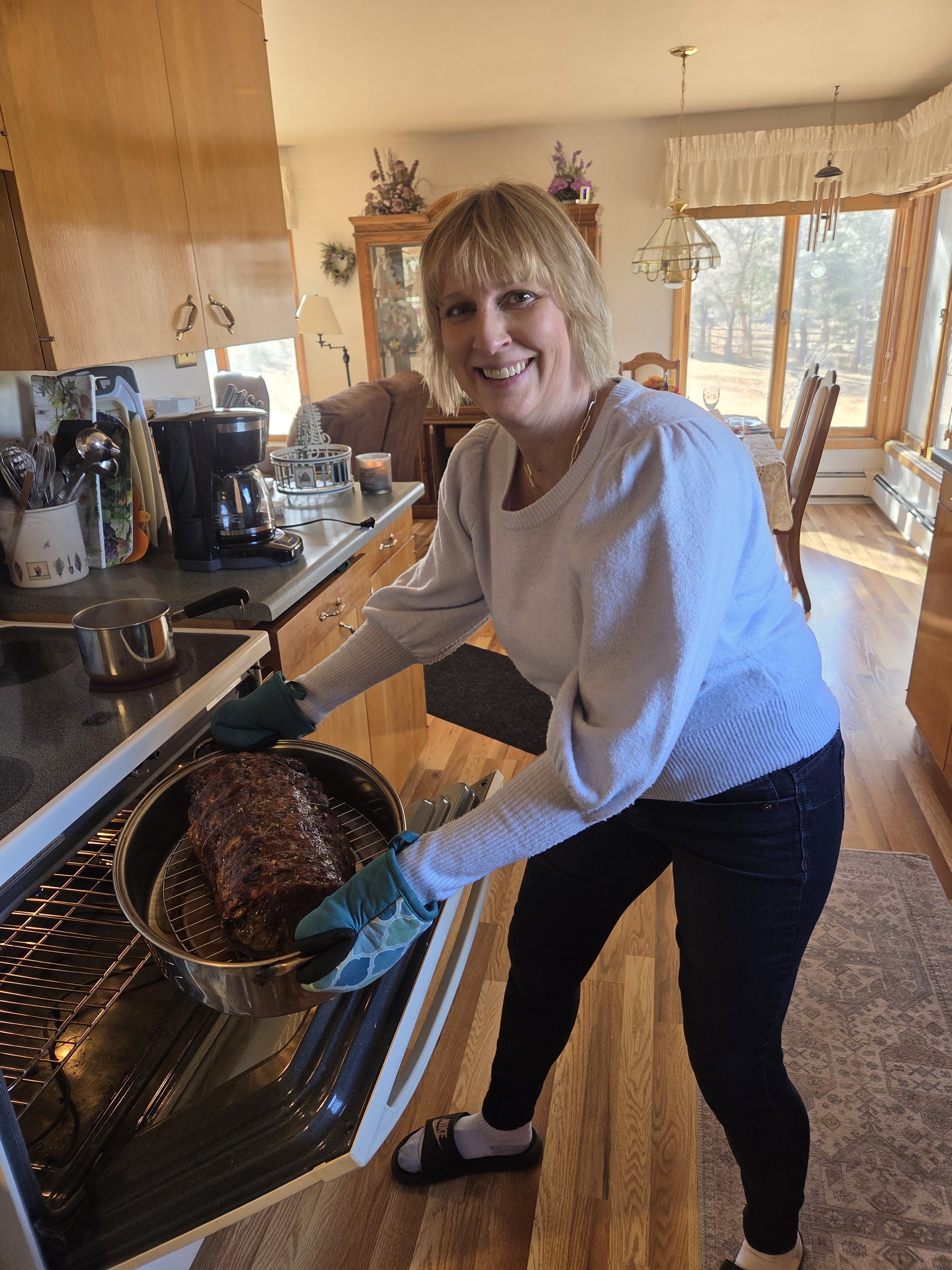 Woman pulling a roast out of an oven