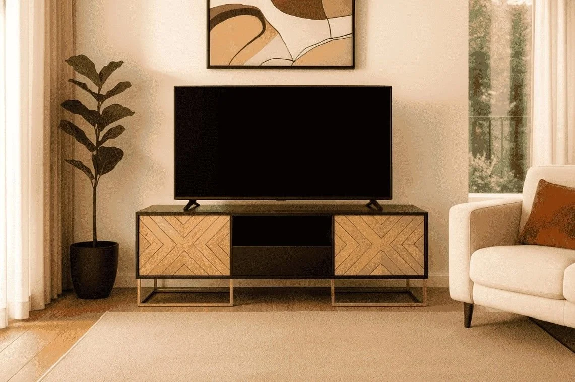 Living room with a flat-screen TV on a modern wooden TV stand, a potted fiddle leaf fig plant on the left, a beige armchair with a brown pillow on the right, a window with beige curtains, and an abstract painting above the TV.