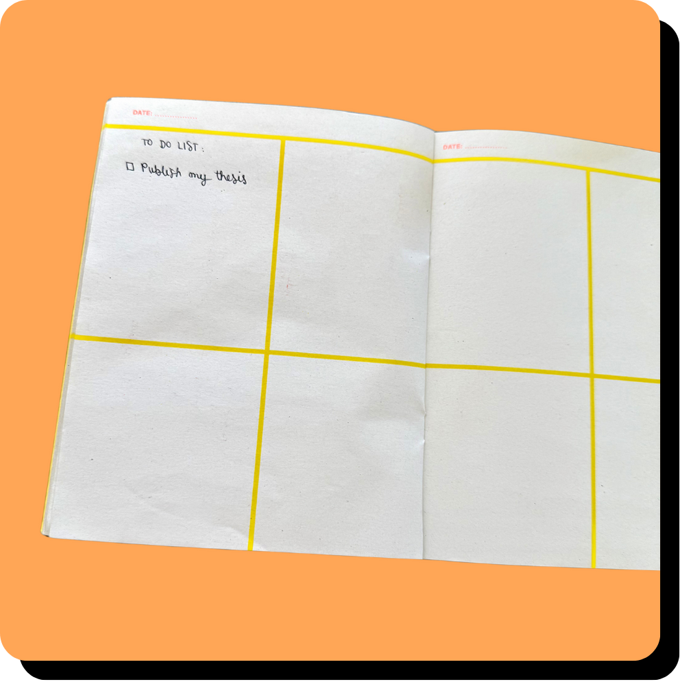 Open planner with yellow grid lines, handwritten to-do list item to publish thesis, on orange background.