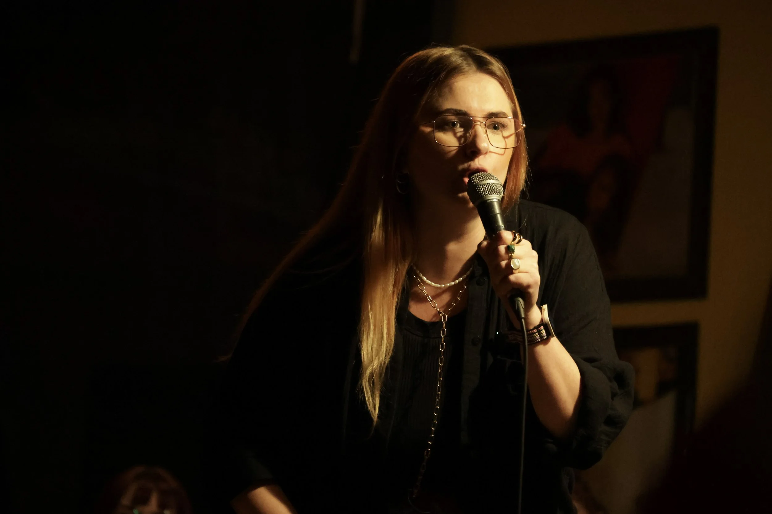 Alina auf einer Bühne mit Mikrofon, inmitten einer Comedy-Performance