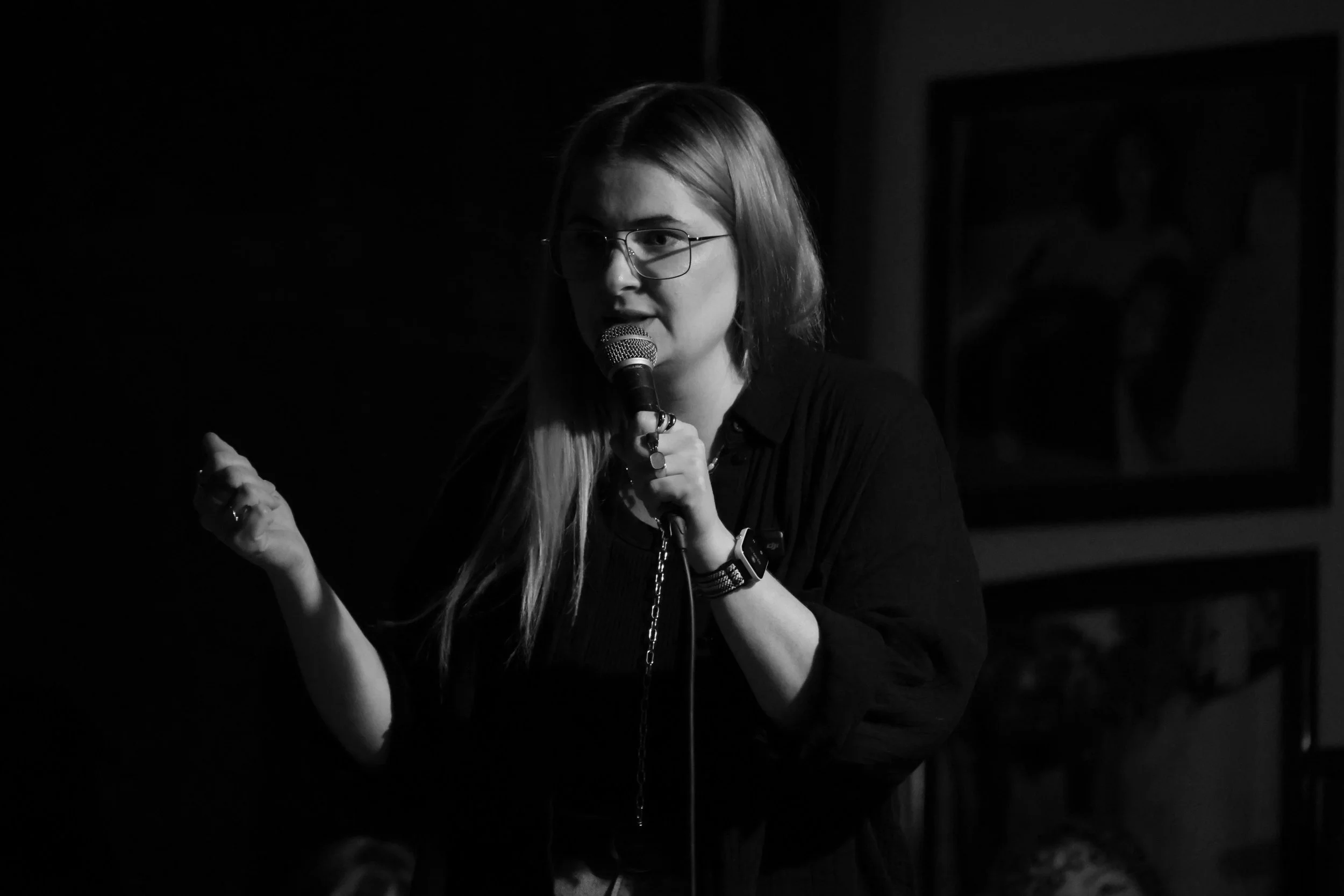 Mit dem Mikrofon in der einen Hand, die andere Hand ist eine geballte Faust schaut Alina bei diesem schwarz-weiß Foto dringlich ins Publikum