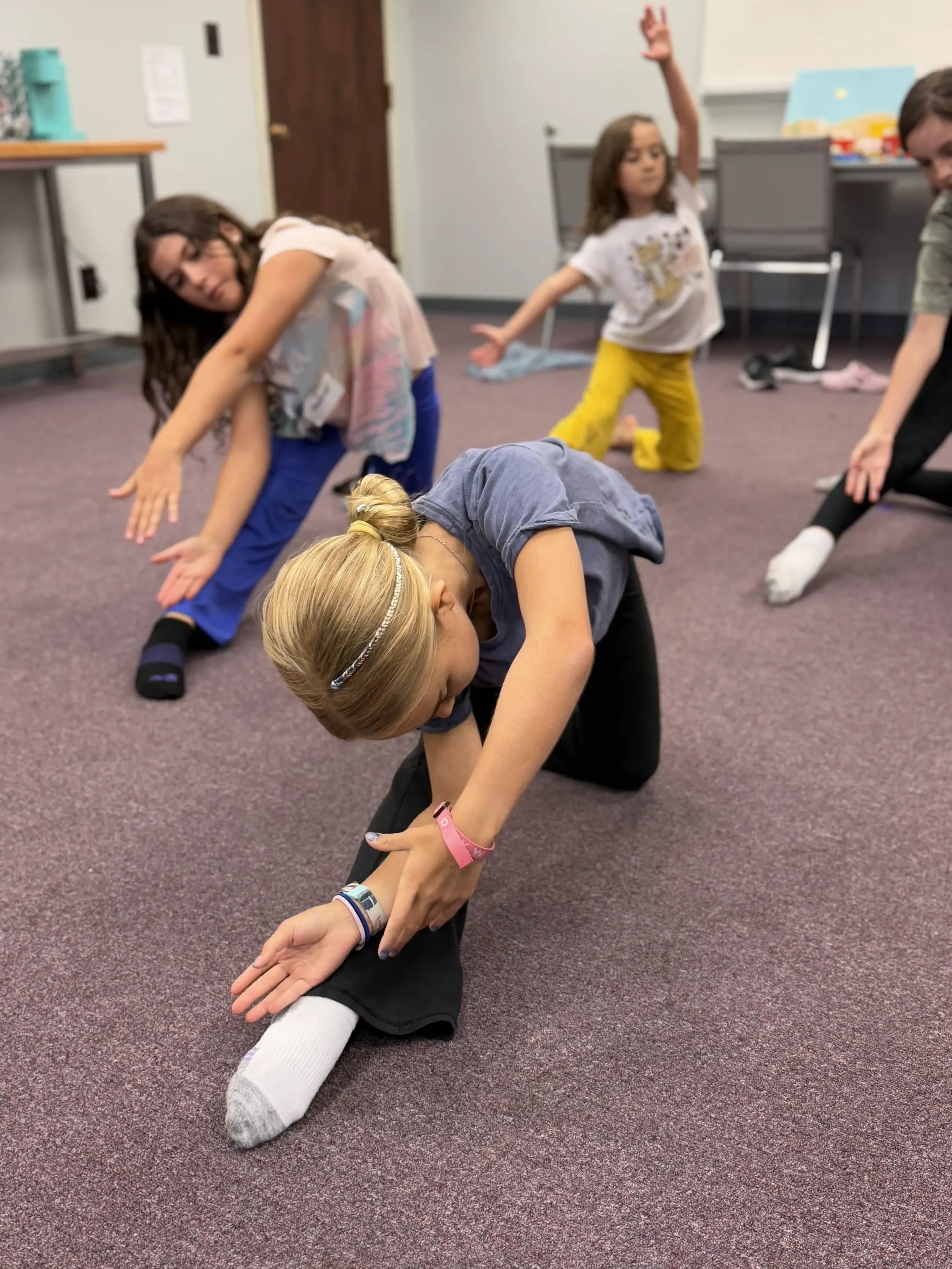 Young dancers kneel and reach forward in expressive worship dance movements during a rehearsal. 
