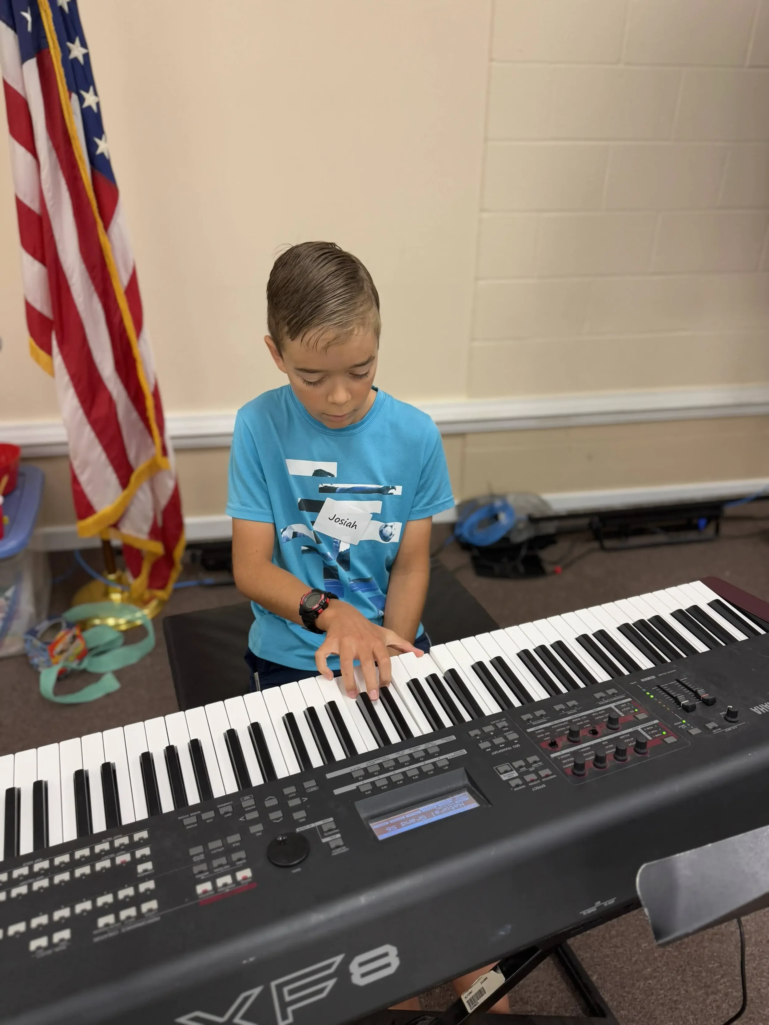 A child plays a keyboard with focused concentration during a band or music class.