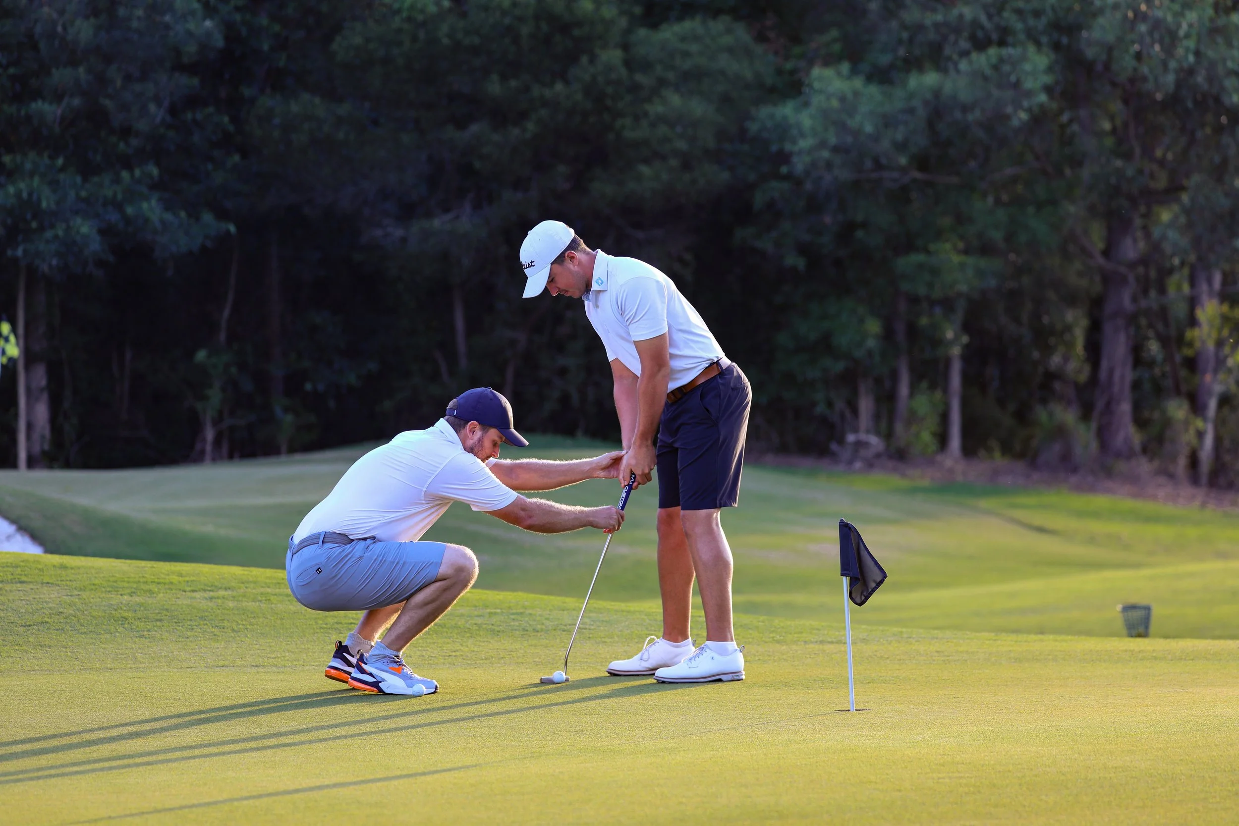 PGA Professional Regan McGovern teaching a student how to putt, during evening sunlight.