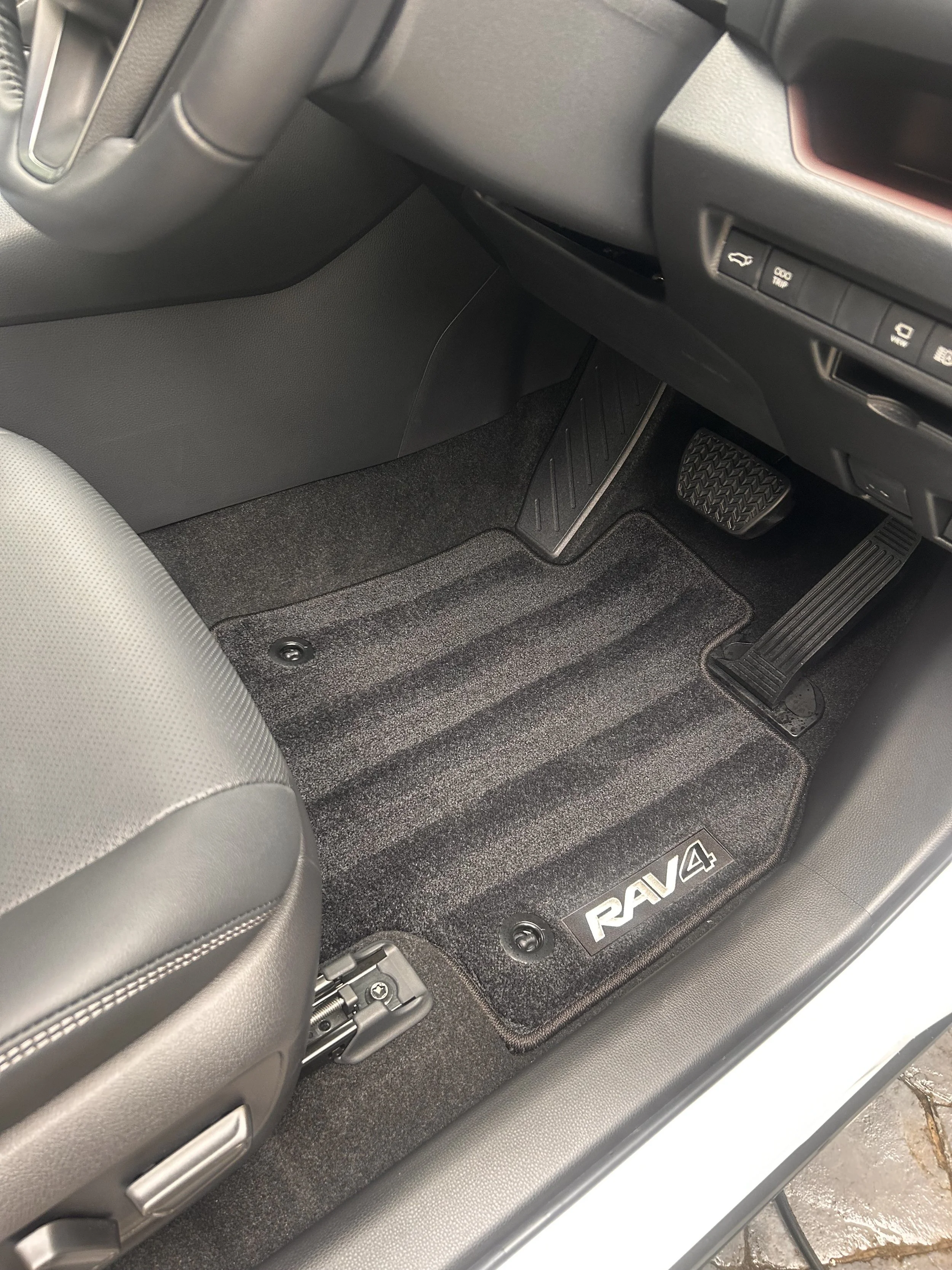 Front interior of a Toyota RAV4 showing the driver's side floor mat and pedals.