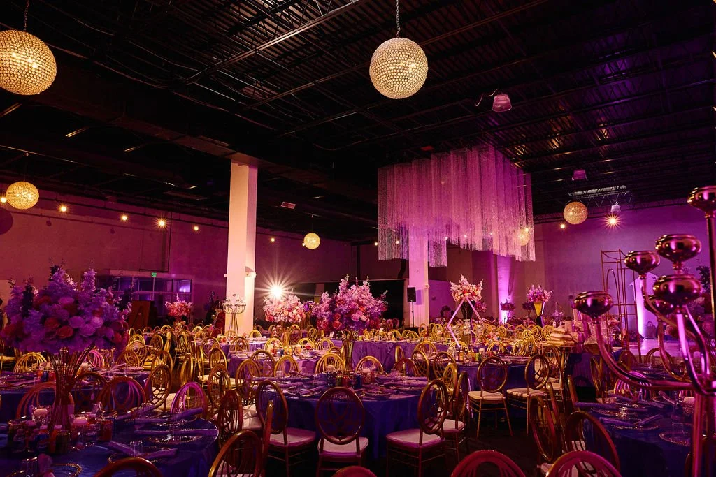 Elegant banquet hall at Grand Occasions in Laurel, Maryland decorated with purple and pink floral centerpieces, gold chairs, and soft lighting for a formal celebration