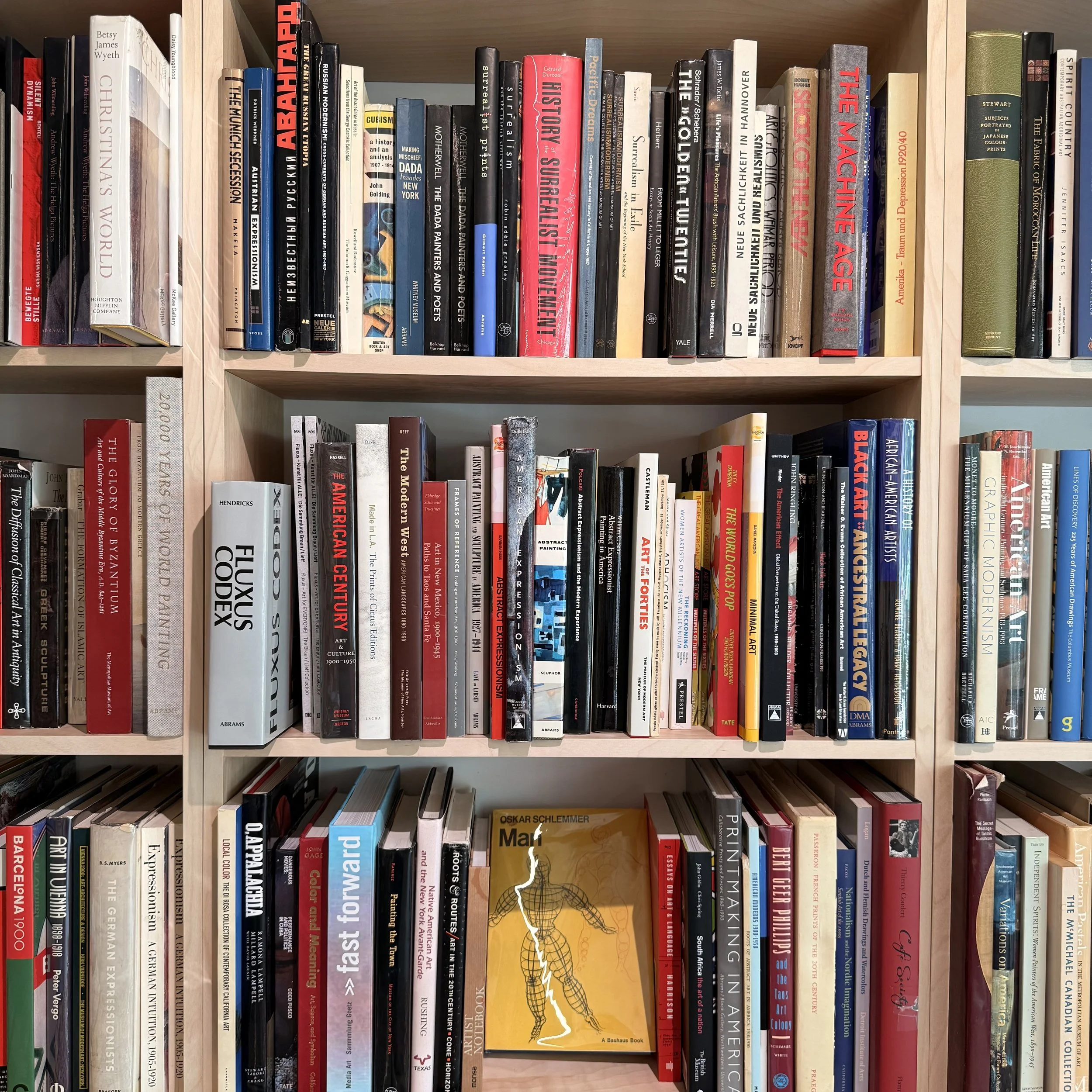A wooden bookshelf filled with colorful books, mostly in portrait orientation, with a few landscape ones, arranged neatly.