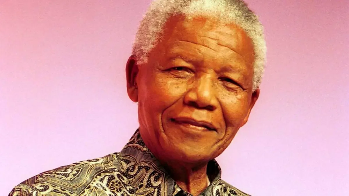 Nelson Mandela standing in a patterned shirt against a pink background
