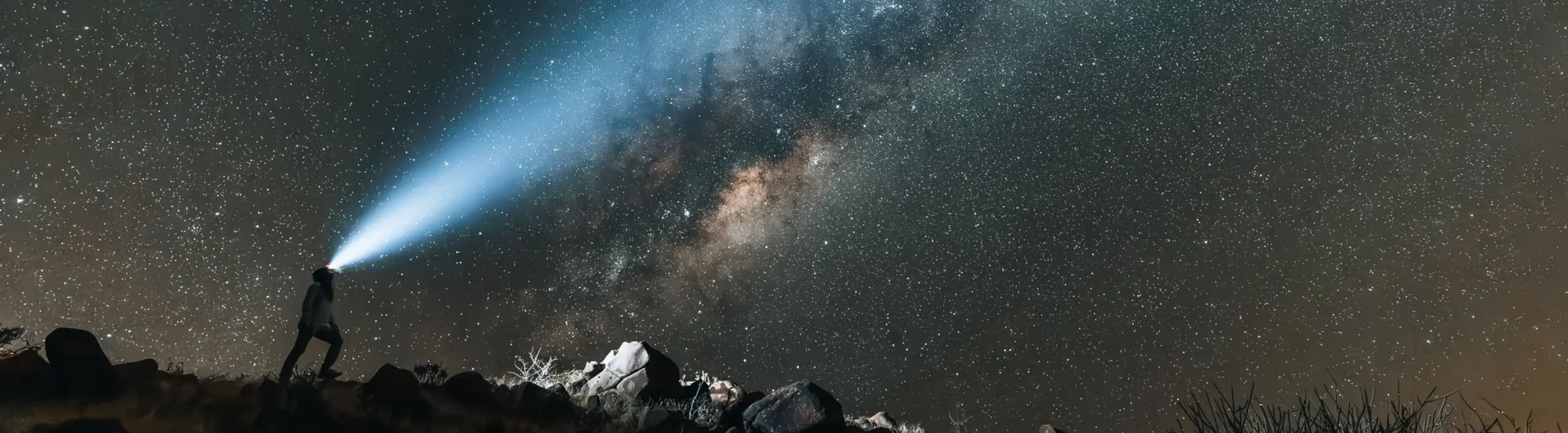 Person with a headlamp looking out into the milky way