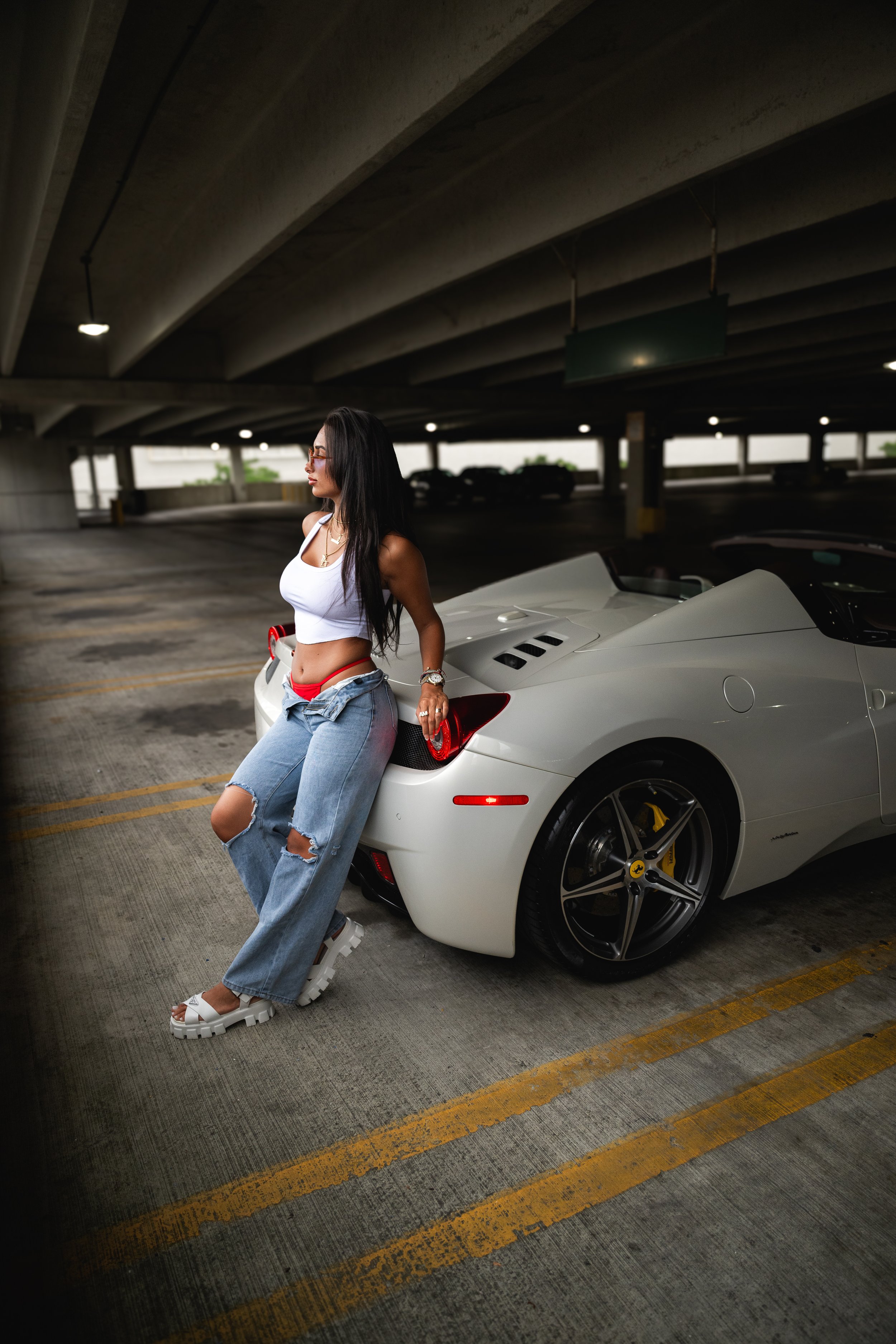 woman leaning on a Ferrari 458 in an a parking garage structure