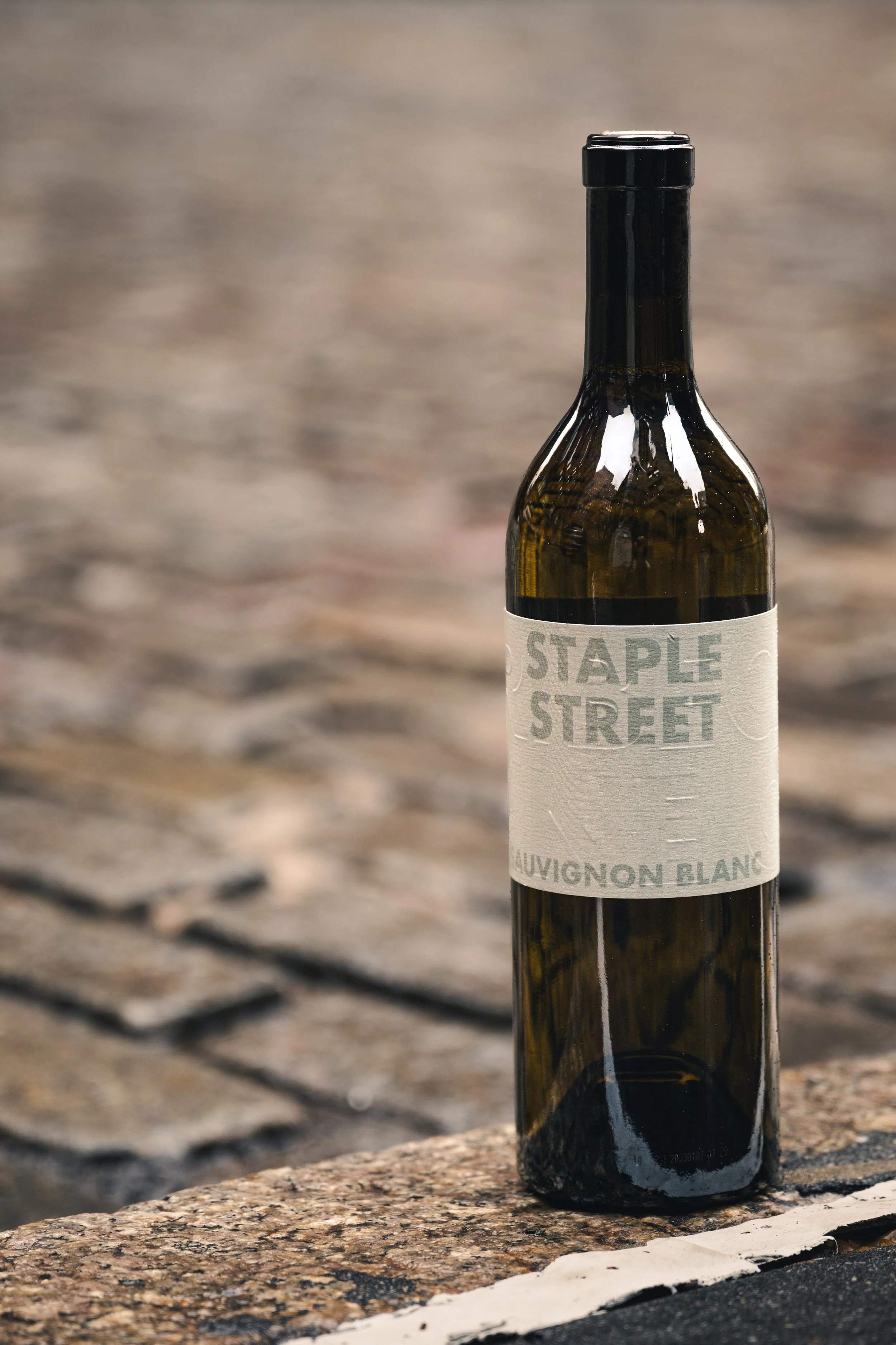 Detailed wine bottle sitting on the curb of a stone road