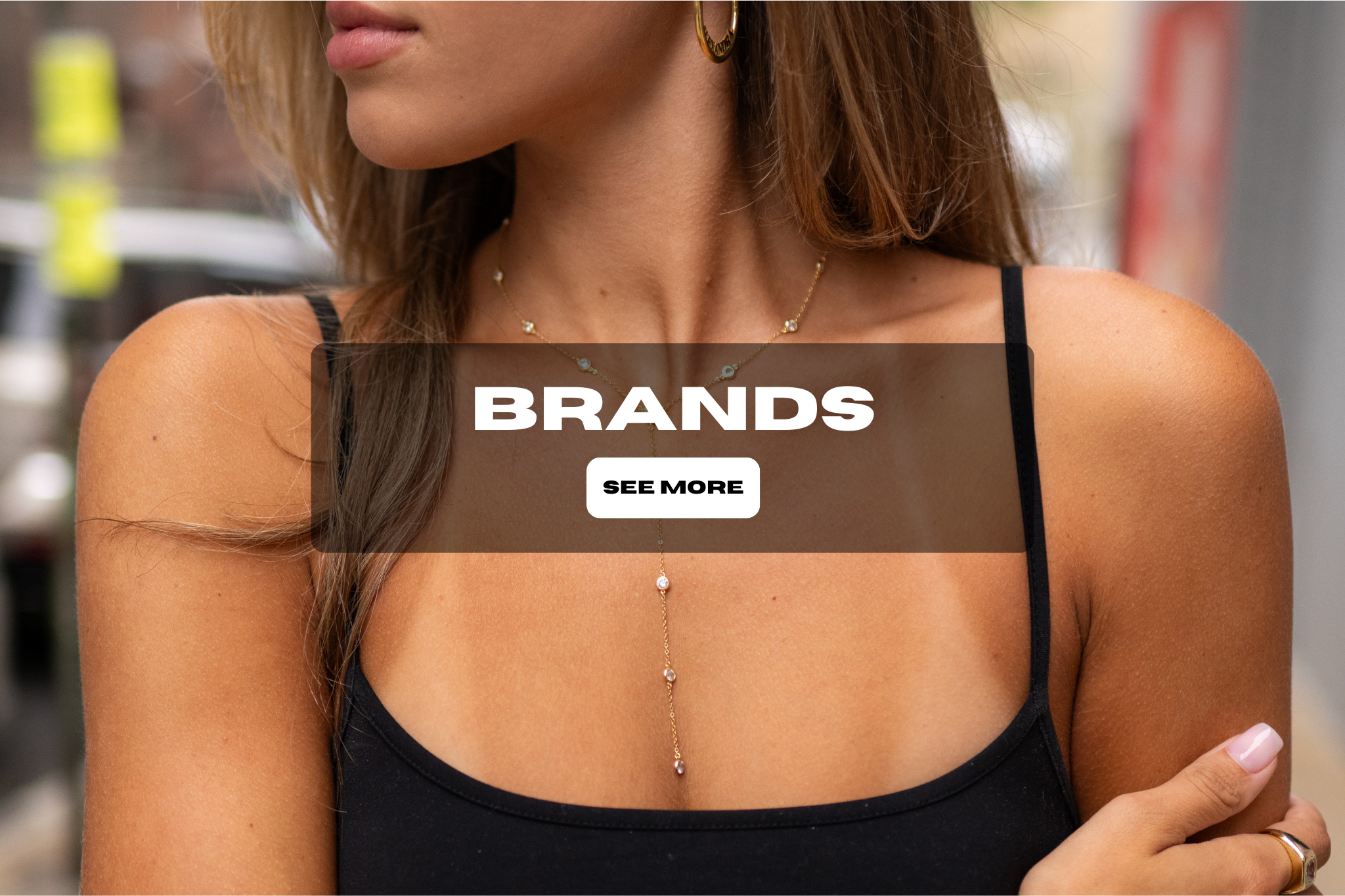 Close-up of a woman wearing a black top and layered jewelry, with a transparent overlay featuring the text 'BRANDS' and a button labeled 'SEE MORE'.