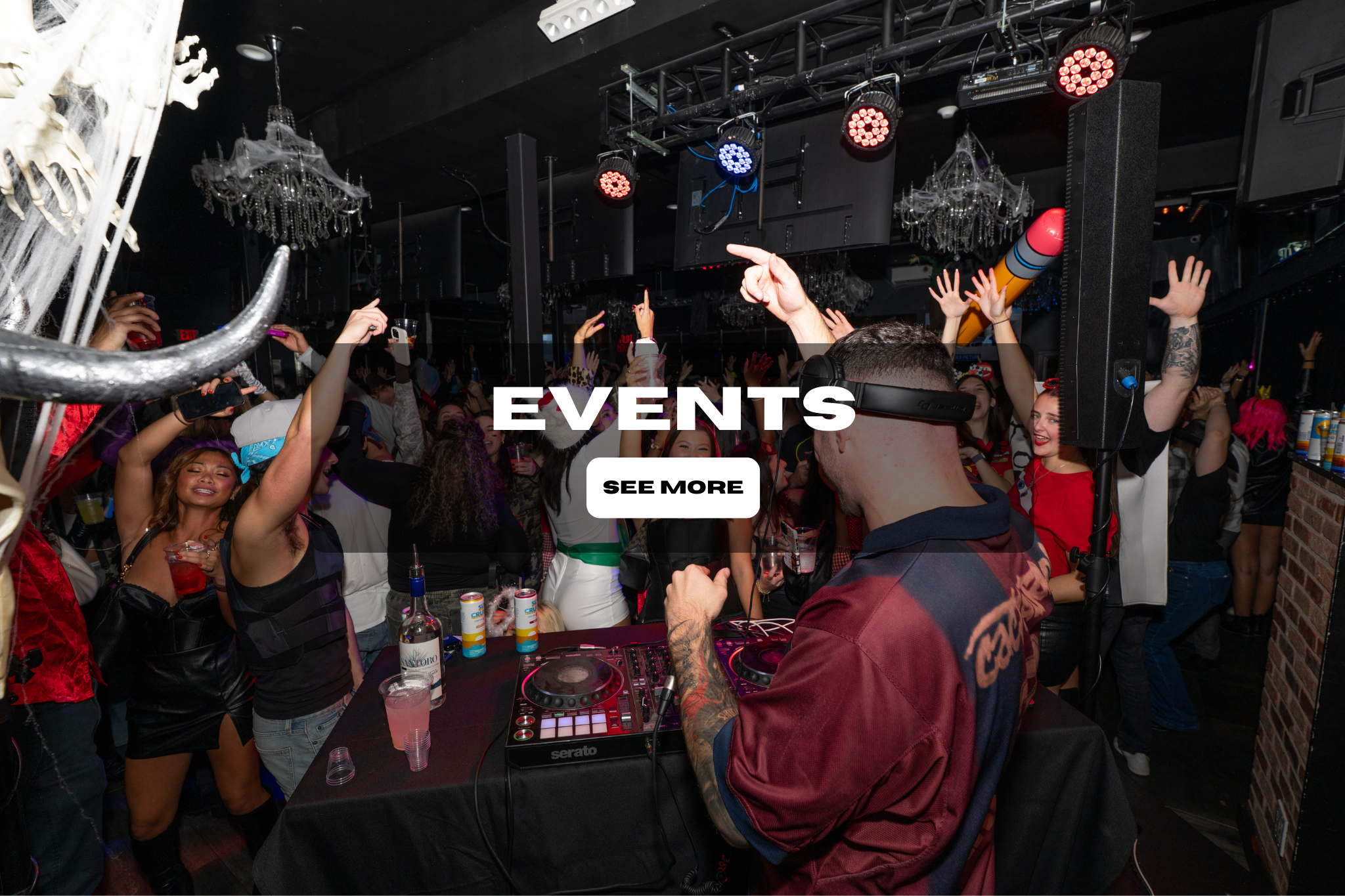 Crowd of people dancing and enjoying a party with a DJ playing music in a nightclub.