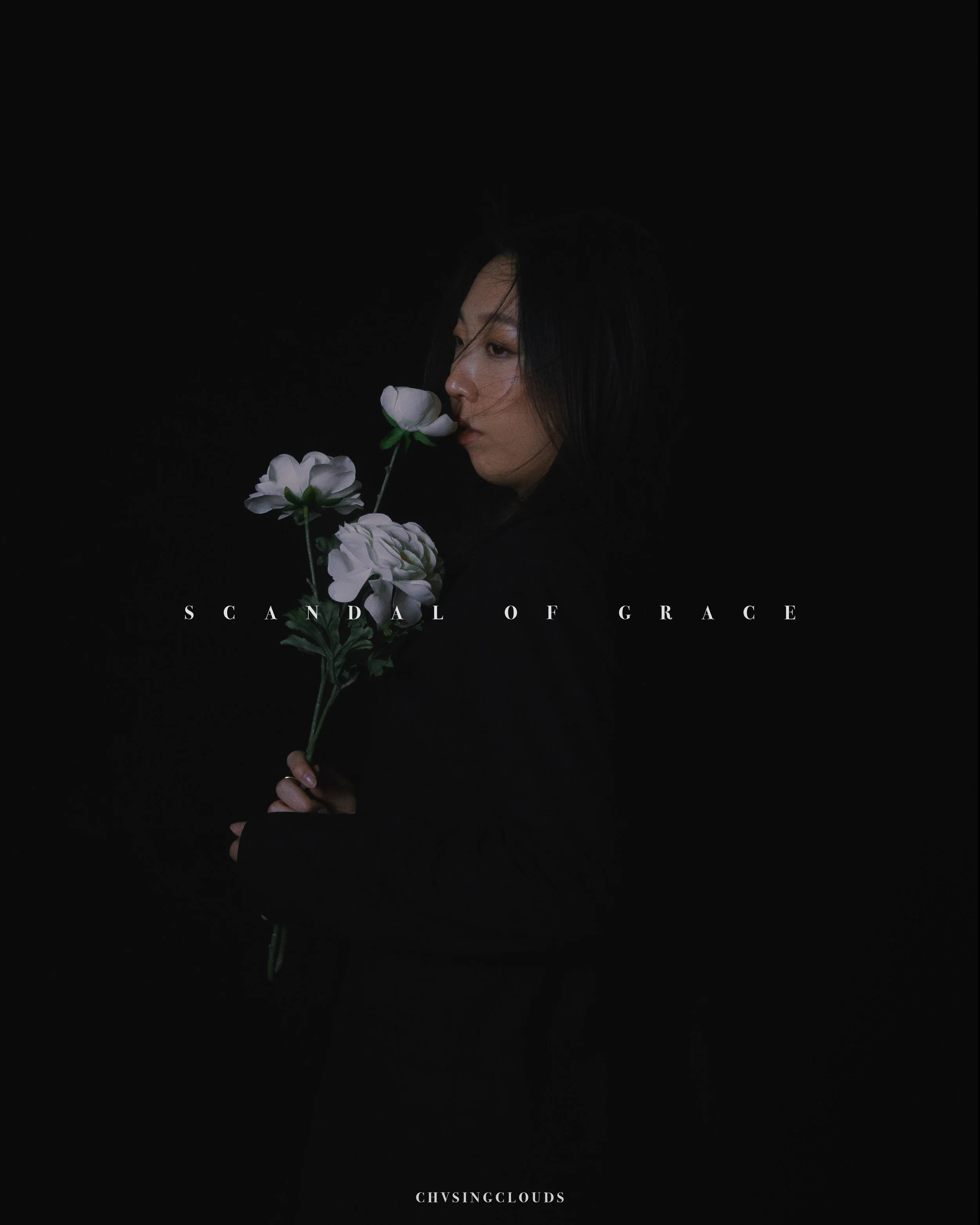 A woman with dark hair holding white flowers against a black background, with the text 'Scandal of Grace' and 'Chvsingclouds' overlayed.