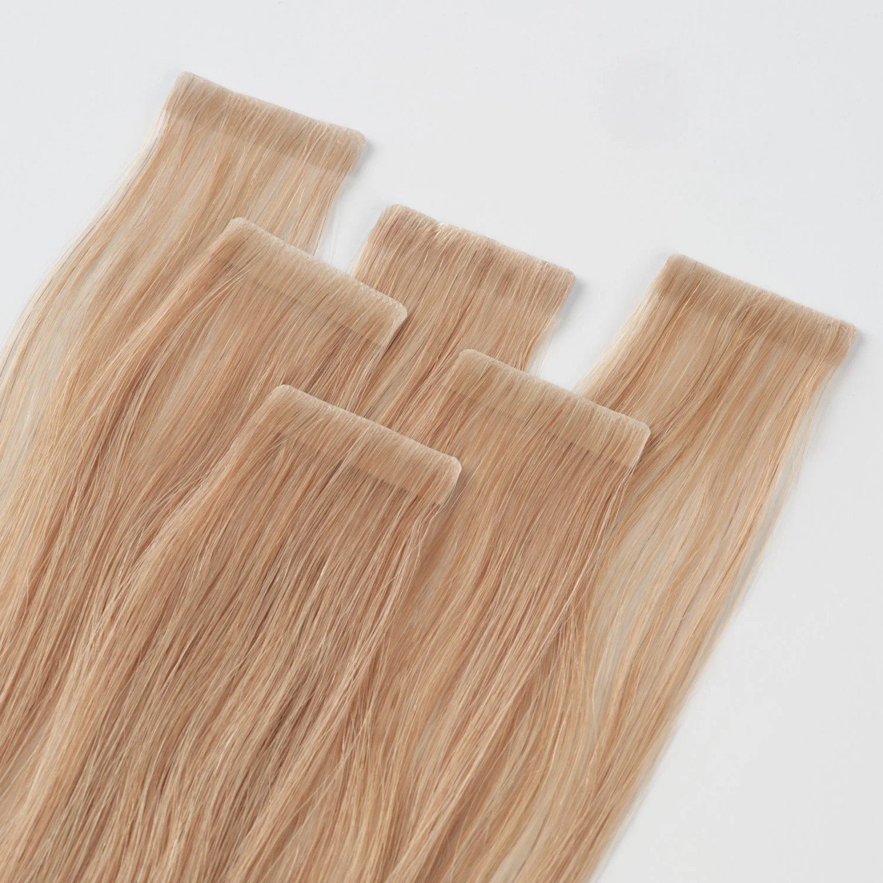 Multiple lengths of blonde hair extension strips arranged on a white background.