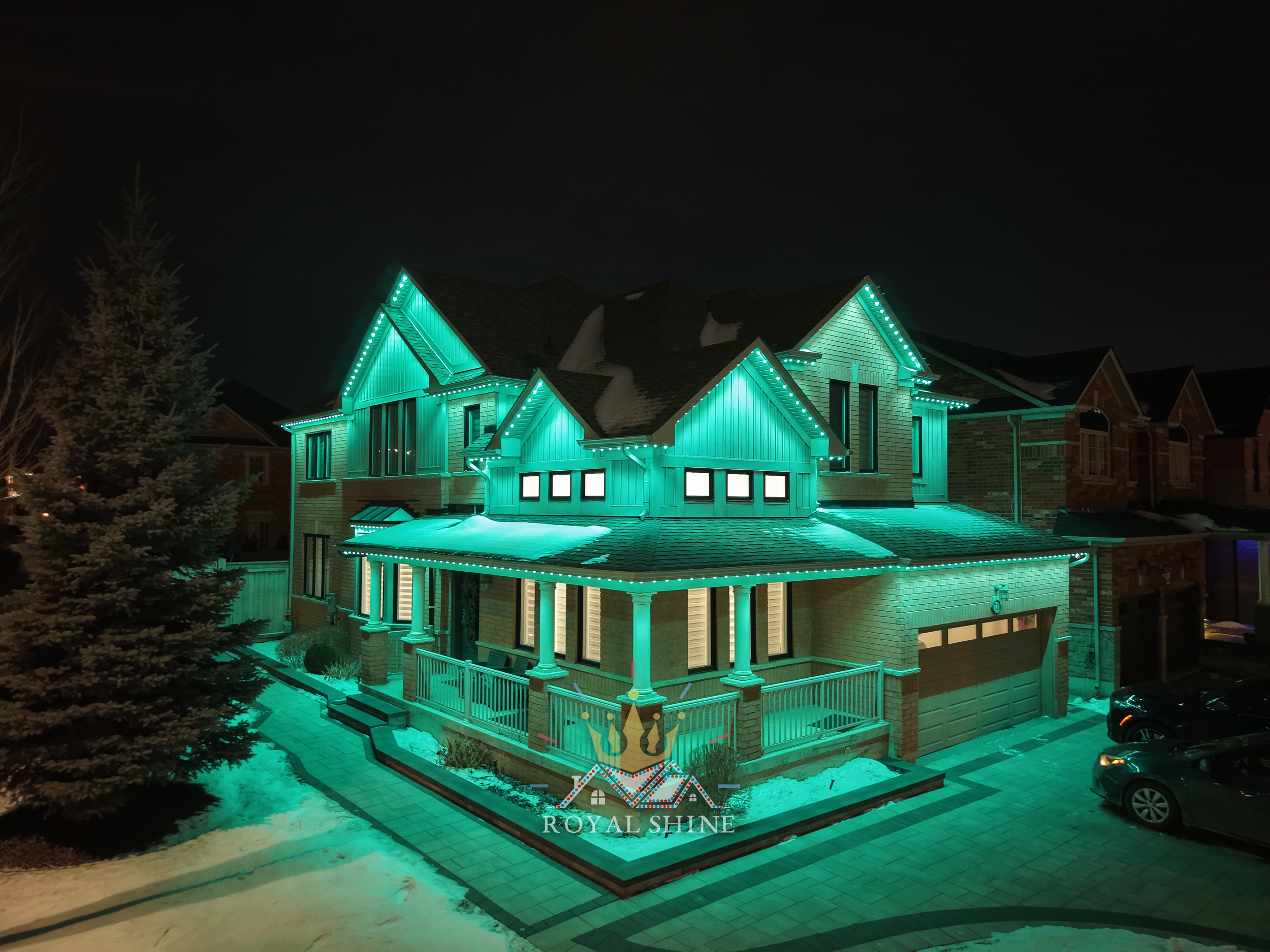 Two-story house decorated with Halloween-themed LED lights outlining roof and porch, displaying a pattern of green, orange, and purple colors. Logo of Royal Shine LED Lighting is visible in the top right corner.