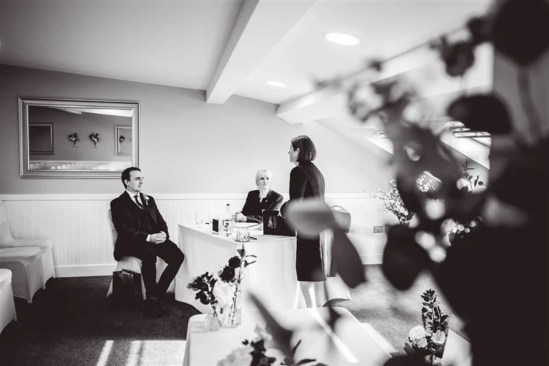 Black & white photo of the groom speaking to the registrars at The Darenth