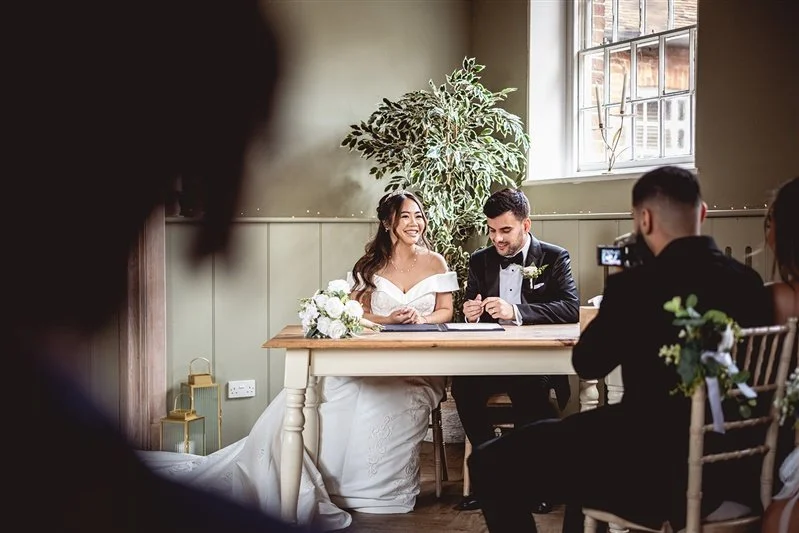 Colour photo of the bride and groom signing the register. Wedding Photographer - at The Secret Garden- Kent