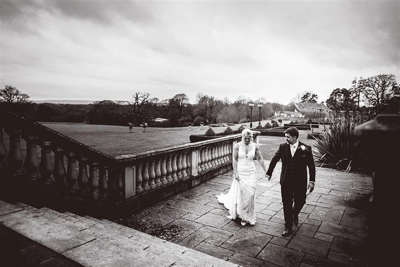 Bride and groom walking up the stairs after their wedding portraits making their way back to the reception. West Sussex wedding photography at - Matt Rock