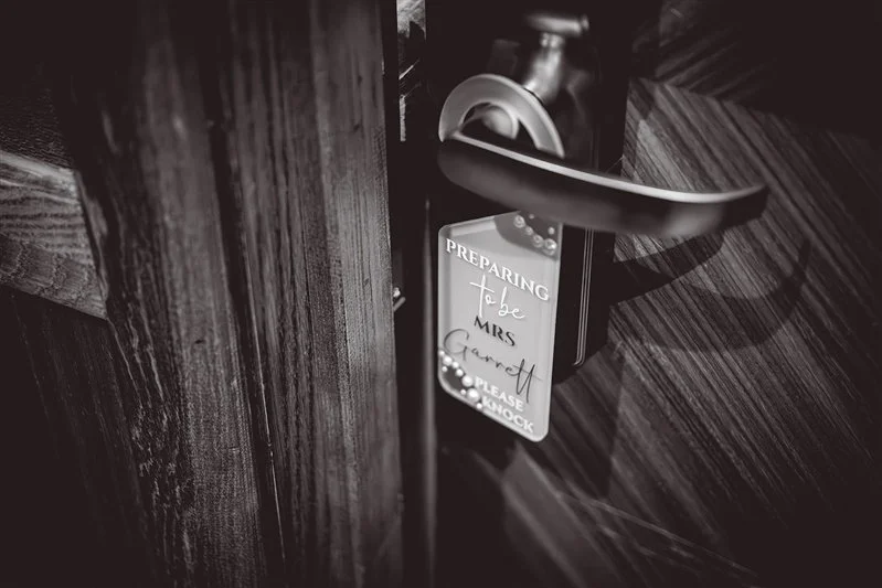 Black & white photo of the room door handle with the brides name on it