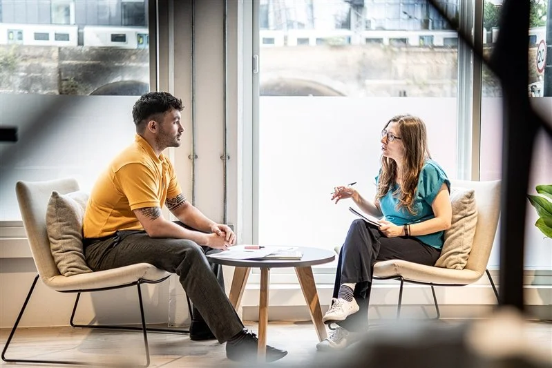 Commercial shoot with two staff having a meeting at a table in an open office in London