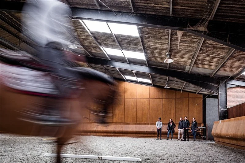 Commercial equestrian shoot - people looking at a horse and Rider walking around the stables - horse is blurred whilst walking in a stable - UK 