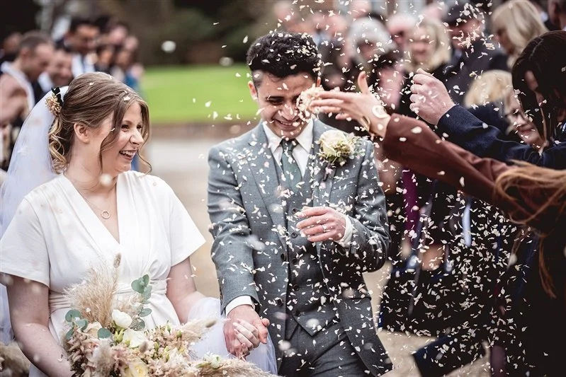Colour photo of the bride and groom haveing their confetti shower at The Oak Barn, Frame Farm in Kent
