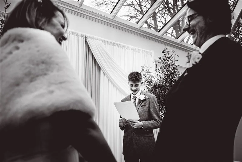 Black & white photo of one of their sons reading during the ceremony at Hayne House