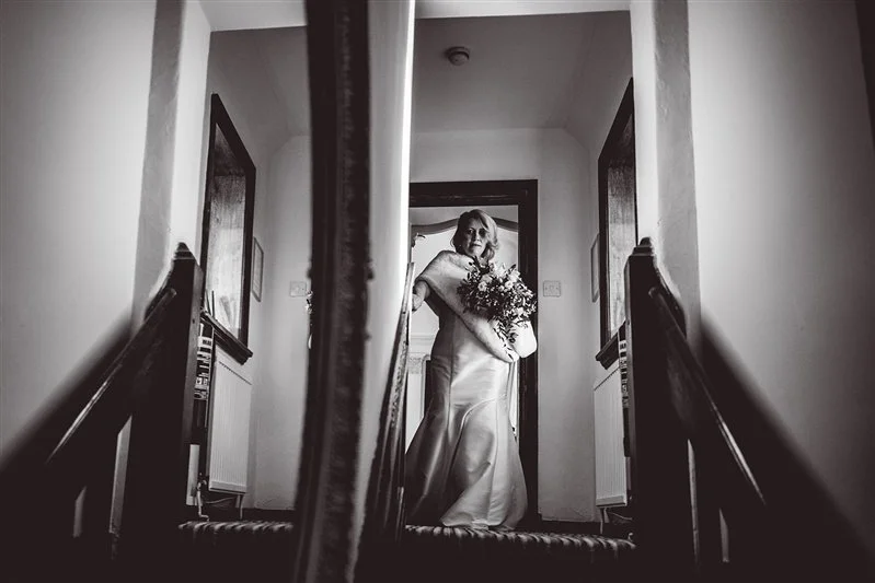 Black & White photo of the bride lwalking down the stairs whilst eaving to go to the ceremony at Hayne House, Kent
