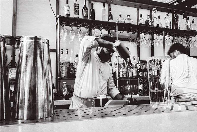 A colour photo of a waiter skilfully making cocktails