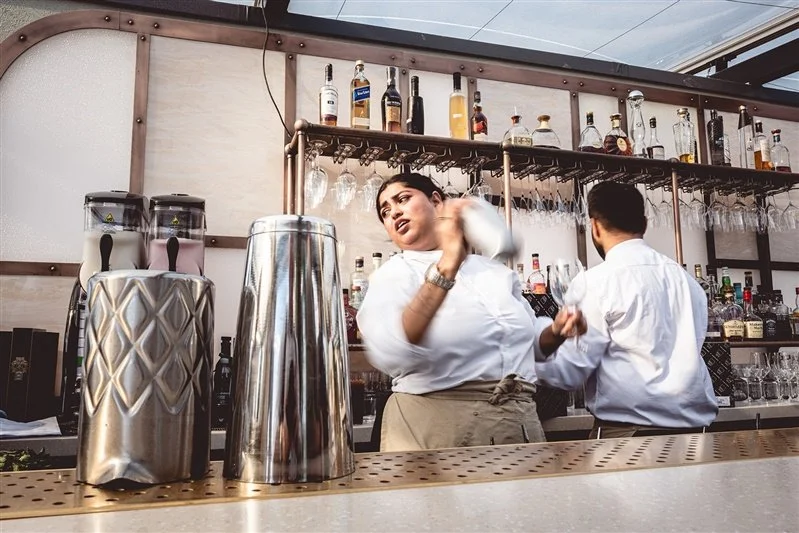 A colour photo of a waitress skilfully making cocktails