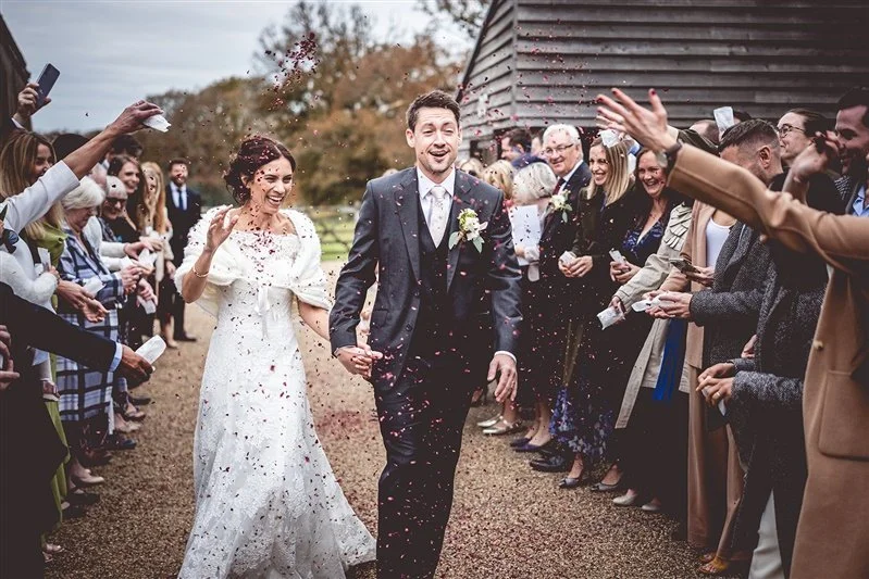 Colour photo of bride and groom walking through the confetti run. Kent wedding photography at The Oak Bar Frame Farm - Matt Rock