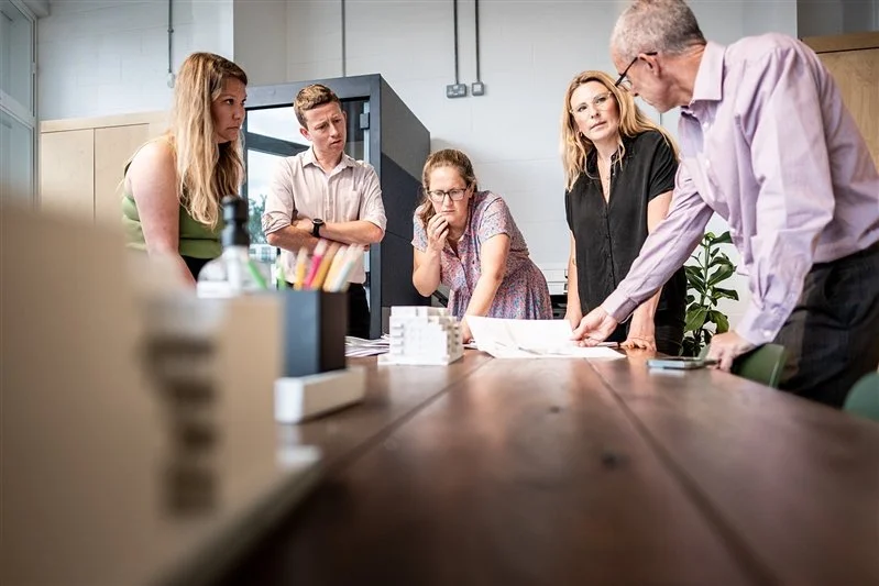 Commercial shoot for a London based surveyors - photo of an office environment - a group of surveyors looking at plans and a scaled model of a building of the office. 