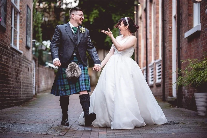 Colour photo of the bride and groom having fun walking near their wedding venue. Kent wedding photographer - One Warrick Park Hotel