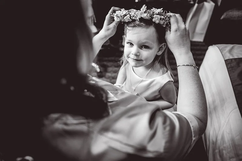 Black & white photo of a flower girl getting her fascinator fitted