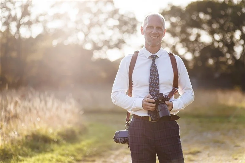 Colour photo of Matt Rock working at a summer wedding wearing shirt and tie using the Holdfast camera strap with a Fujifilm XT5 and an XH1 camera