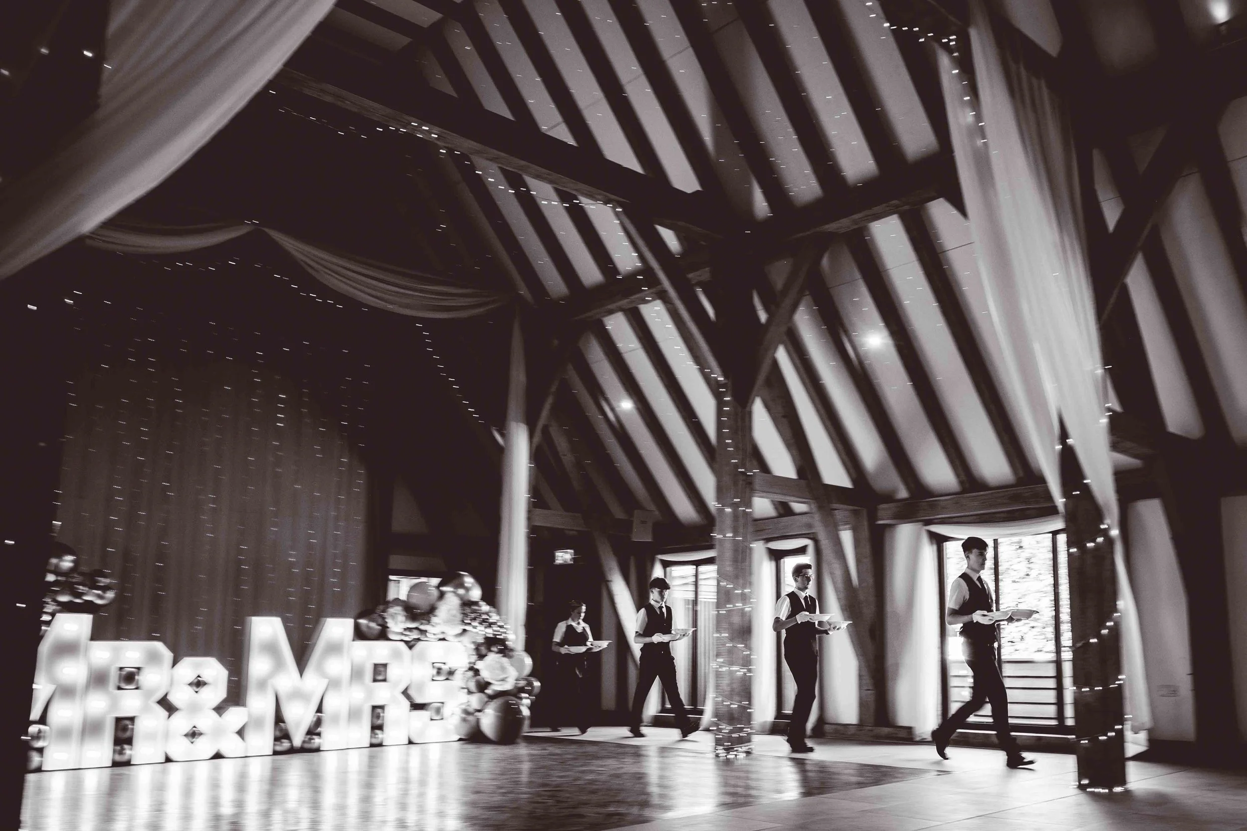 Black & White photo of the waiting staff serving the wedding breakfast at The Old Kent Barn, Kent - UK.